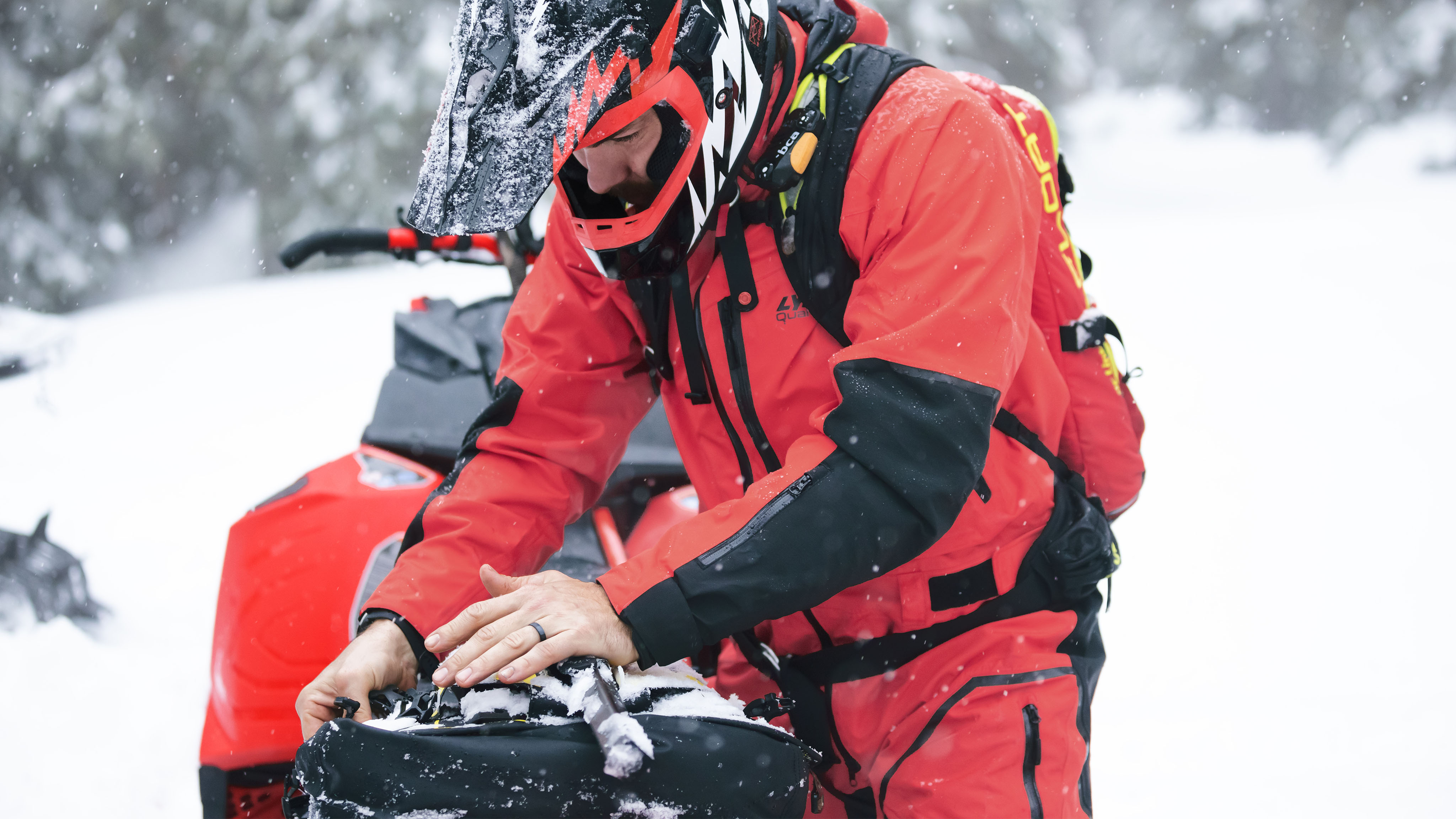 Mann iført Lynx Apparel og forbereder en snøscootertur