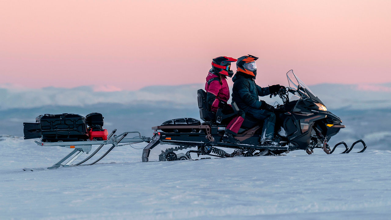 Par som kjører med Lynx Commander Grand Tourer snøscooter på fjellet