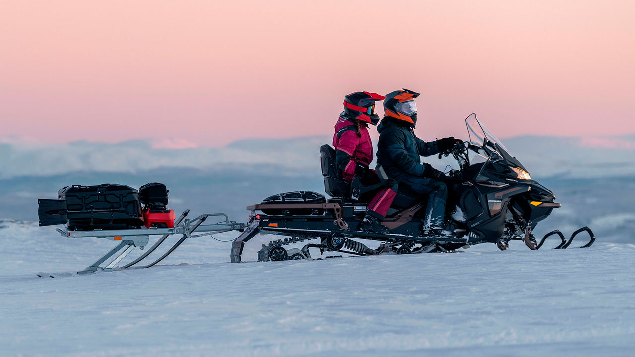 Pariskunta ajamassa Lynx Commander Grand Tourer moottorikelkalla vuoristossa