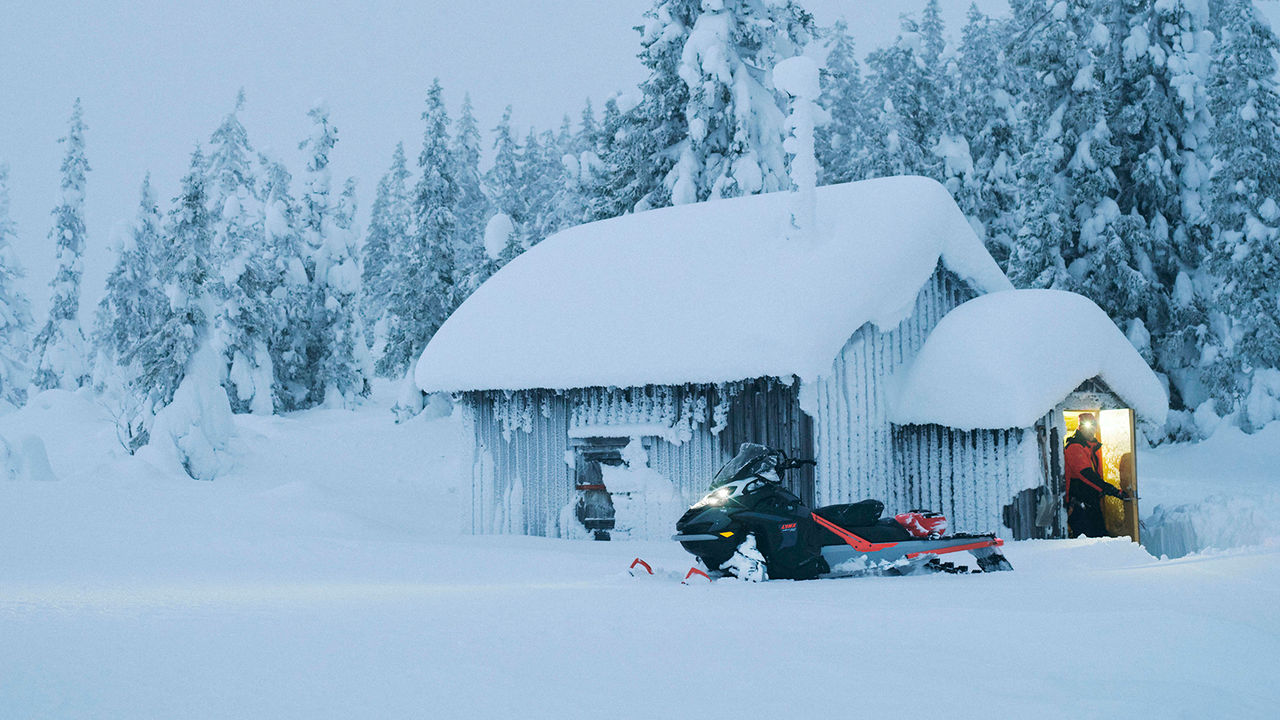 49 Ranger PRO snowmobile parked in front of wilderness cabin