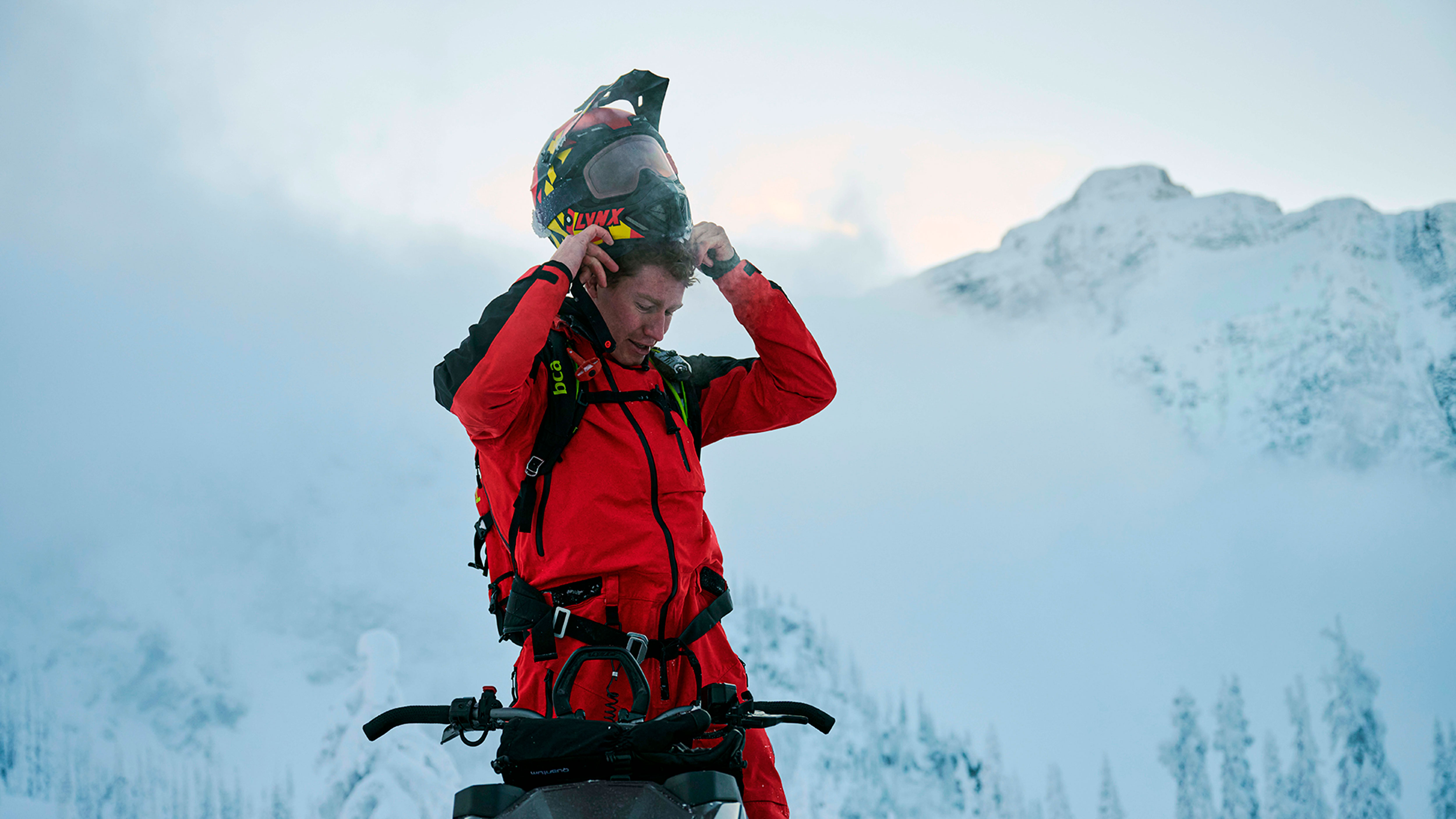 Man standing on his Lynx while putting on his helmet