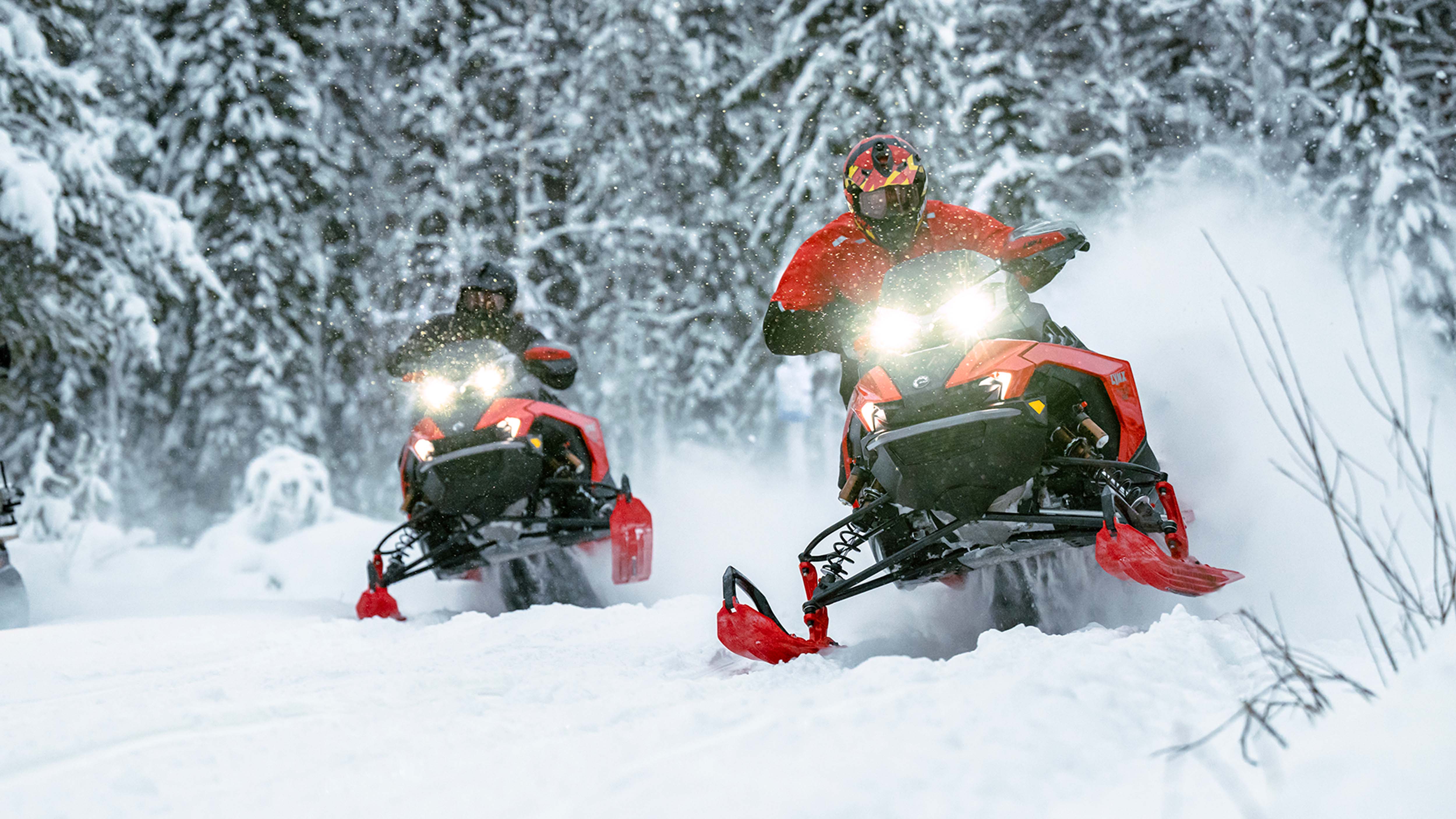 Two Lynx riders snowmobiling in trail
