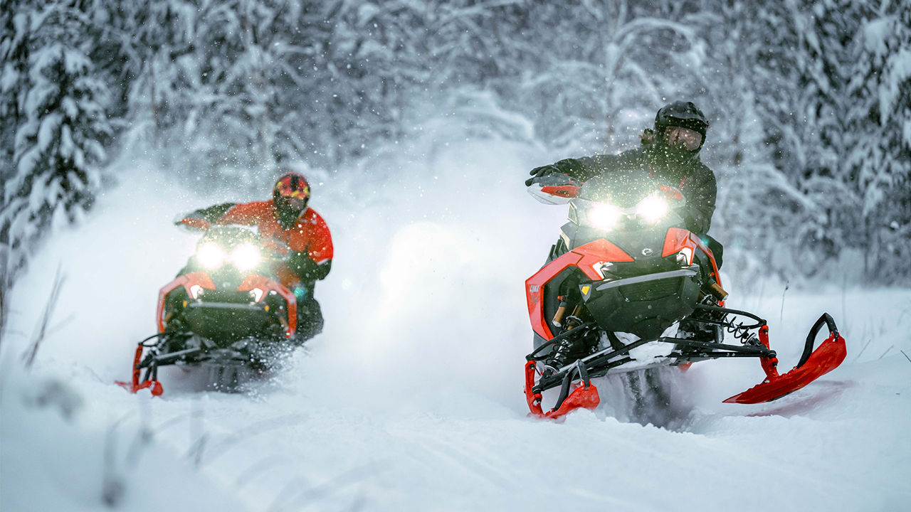 Two Lynx Rave RE snowmobiles cornering on trail