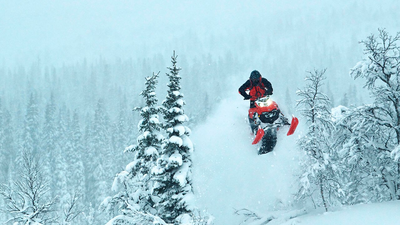 Lynx Shredder RE moottorikelkka hyppäämässä korkealle puiden välissä