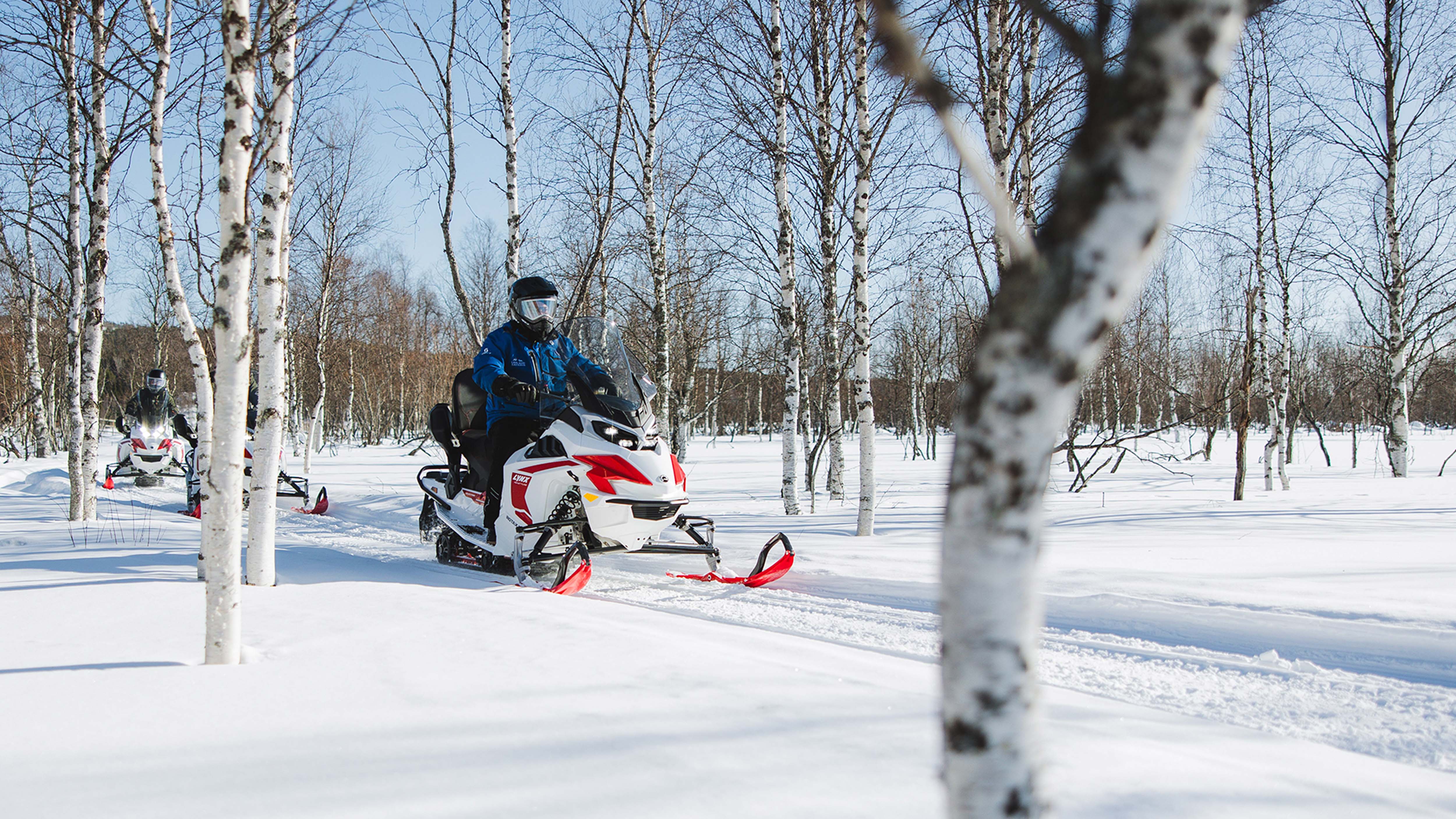 Lynx Adventure Electic moottorikelkka ajamassa mutkaa metsäisellä reitillä