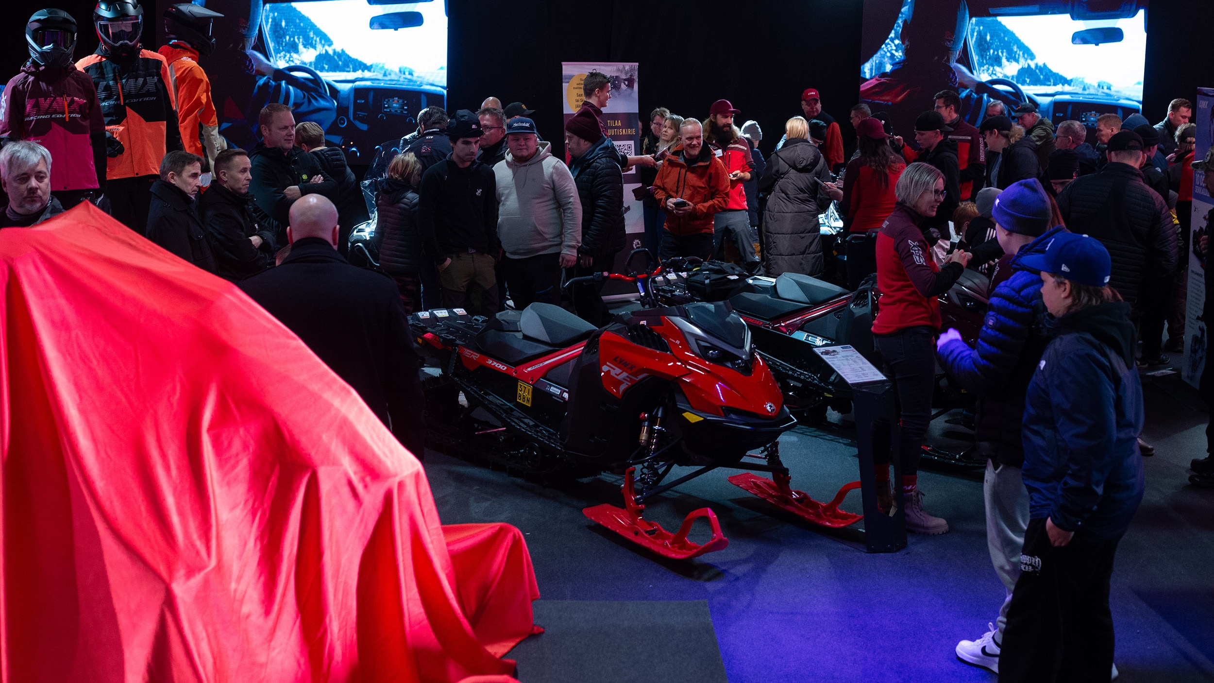 Folk samlet rundt Lynx-snøscootere i en messehall