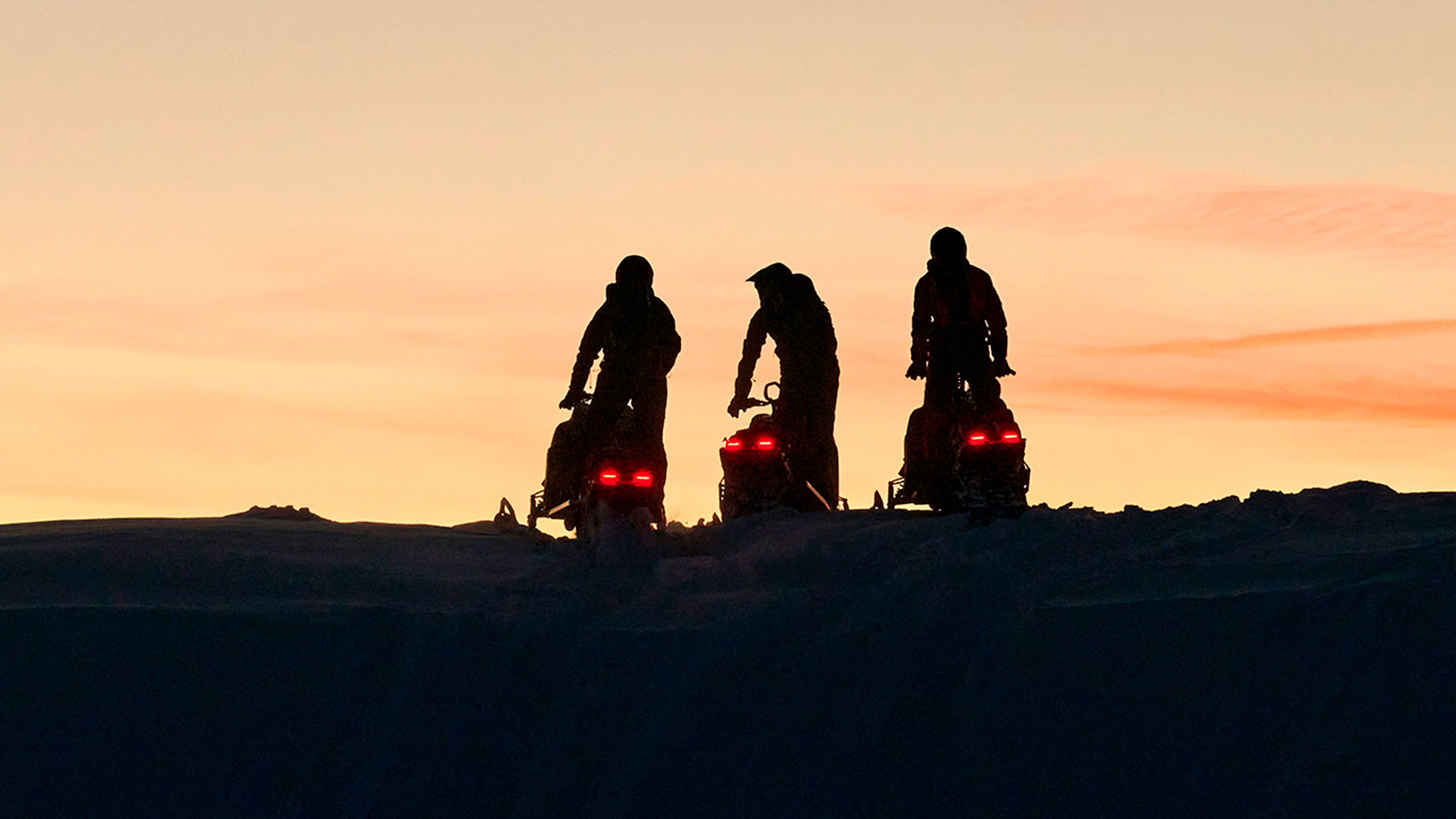 Three Lynx snowmobile riders at dawn