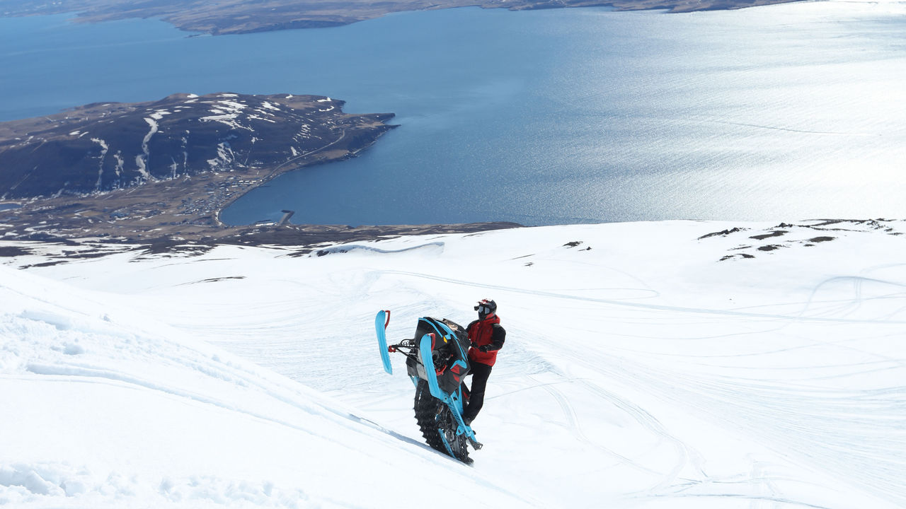 Man going up a hill with a Lynx snowmobile