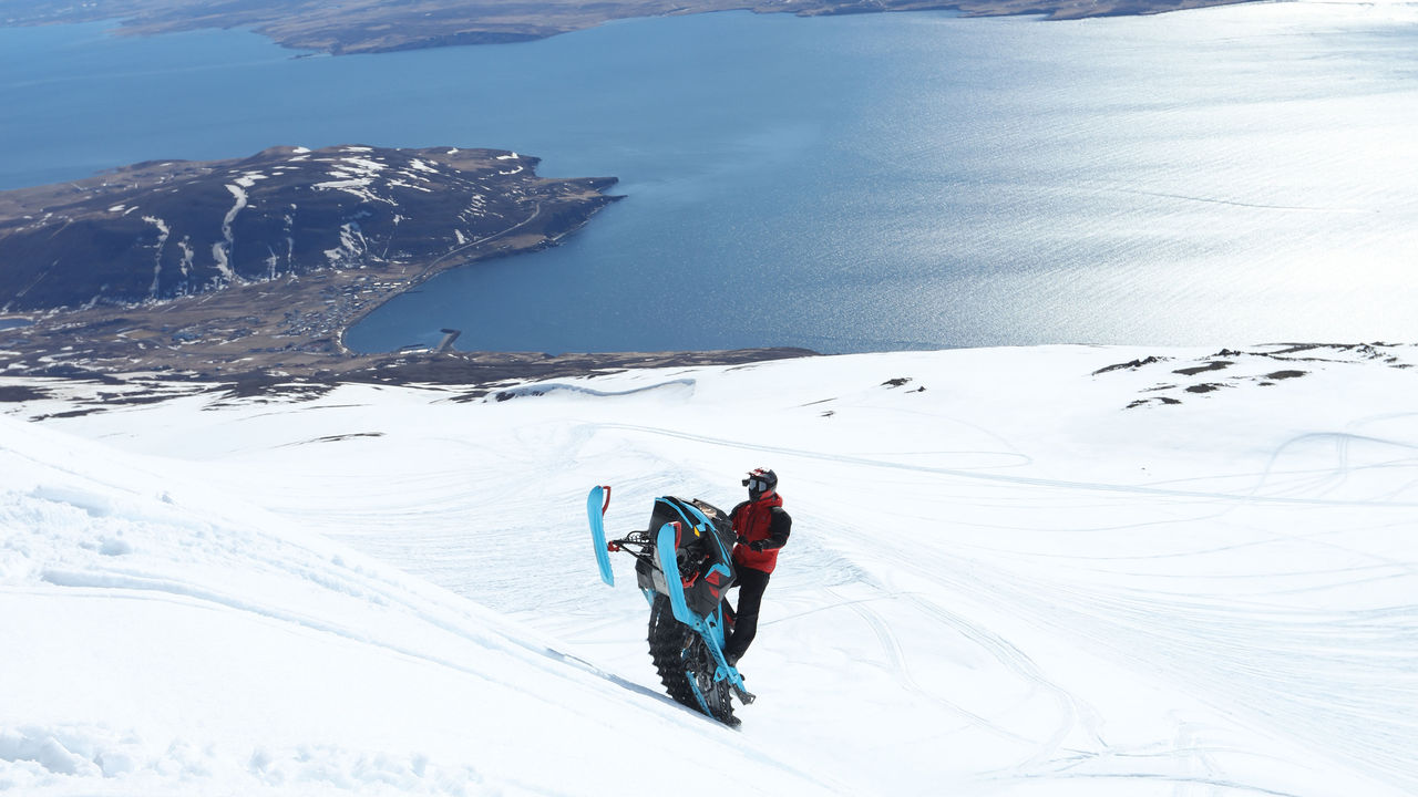 Mann kjører opp en bakke på en Lynx snøscooter