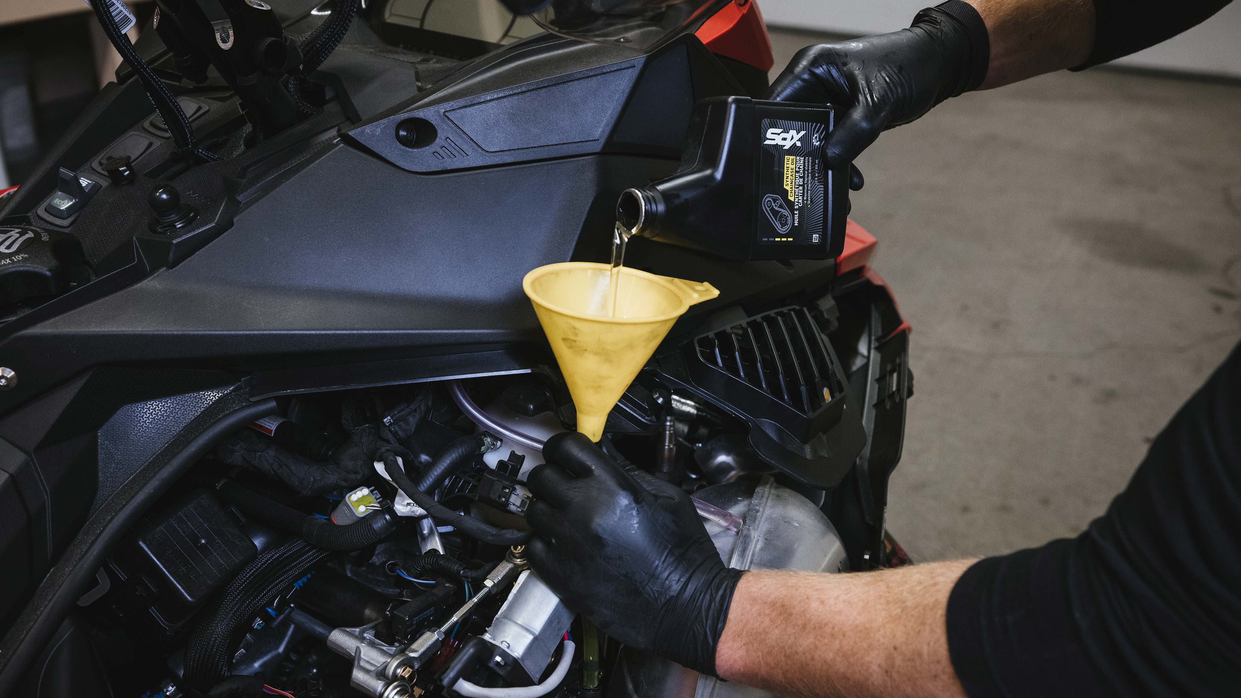 Man changing the chaincase oil of his Lynx snowmobile