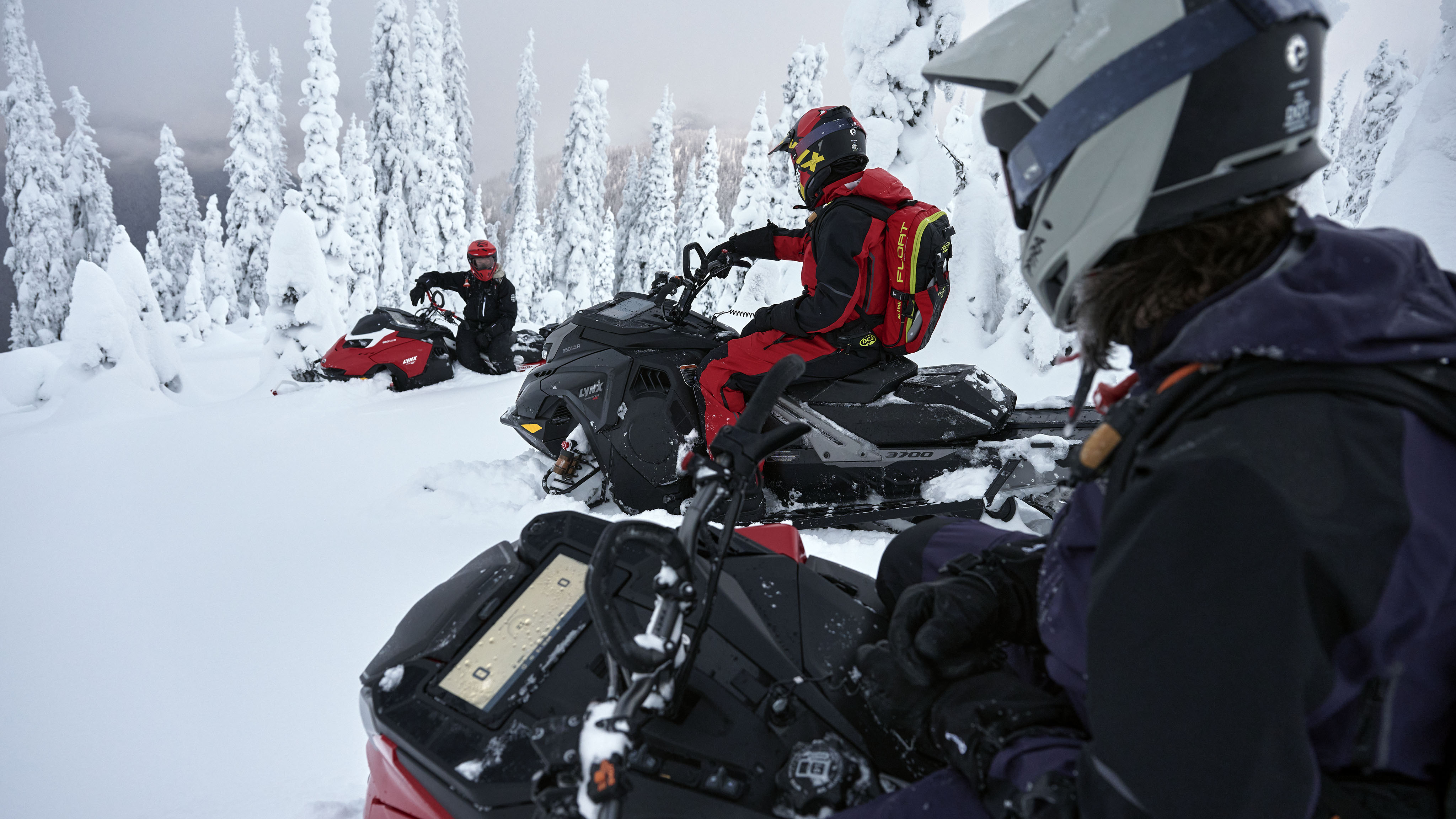 Three Lynx riders on their snowmobiles