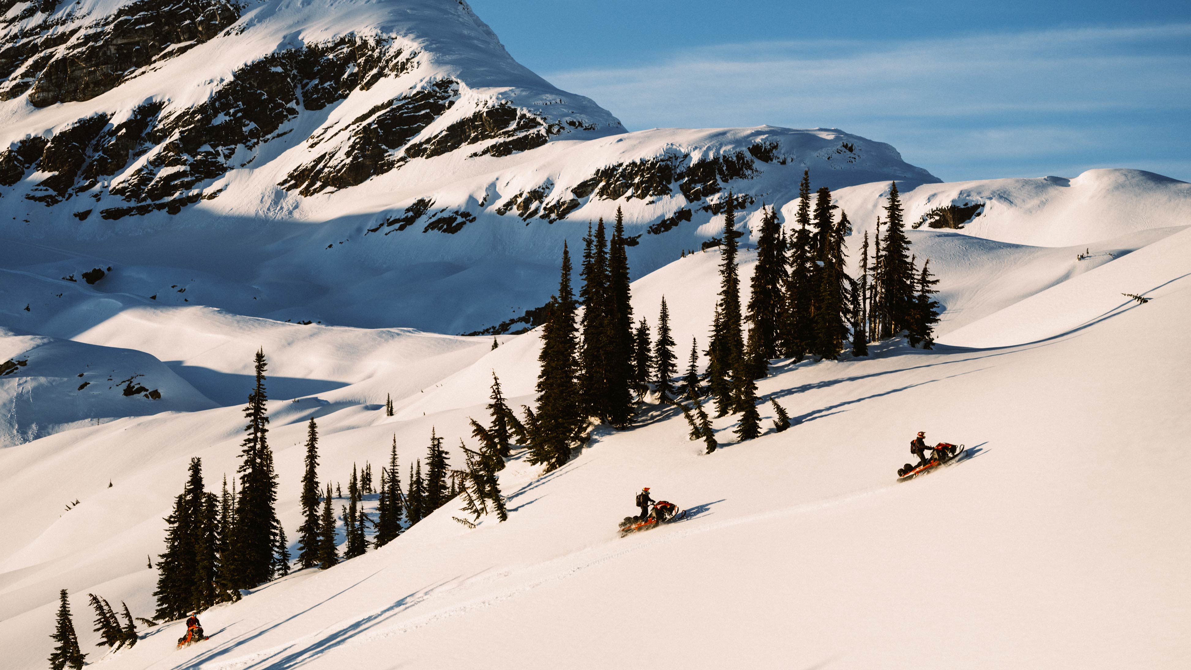 3 Lynx riders snowmobiling in a mountain