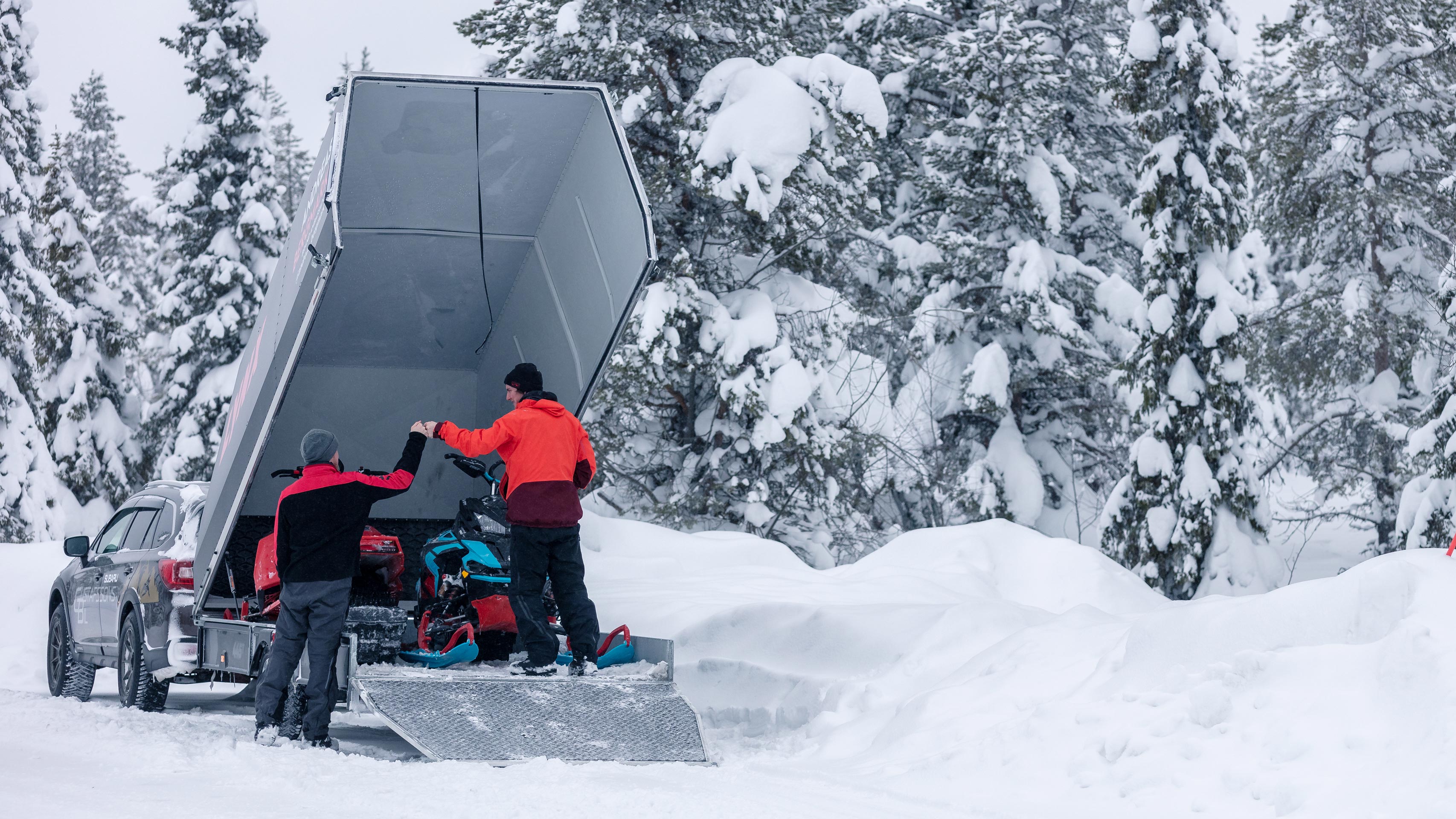 Two snowmobile riders loading their Lynx snowmobiles