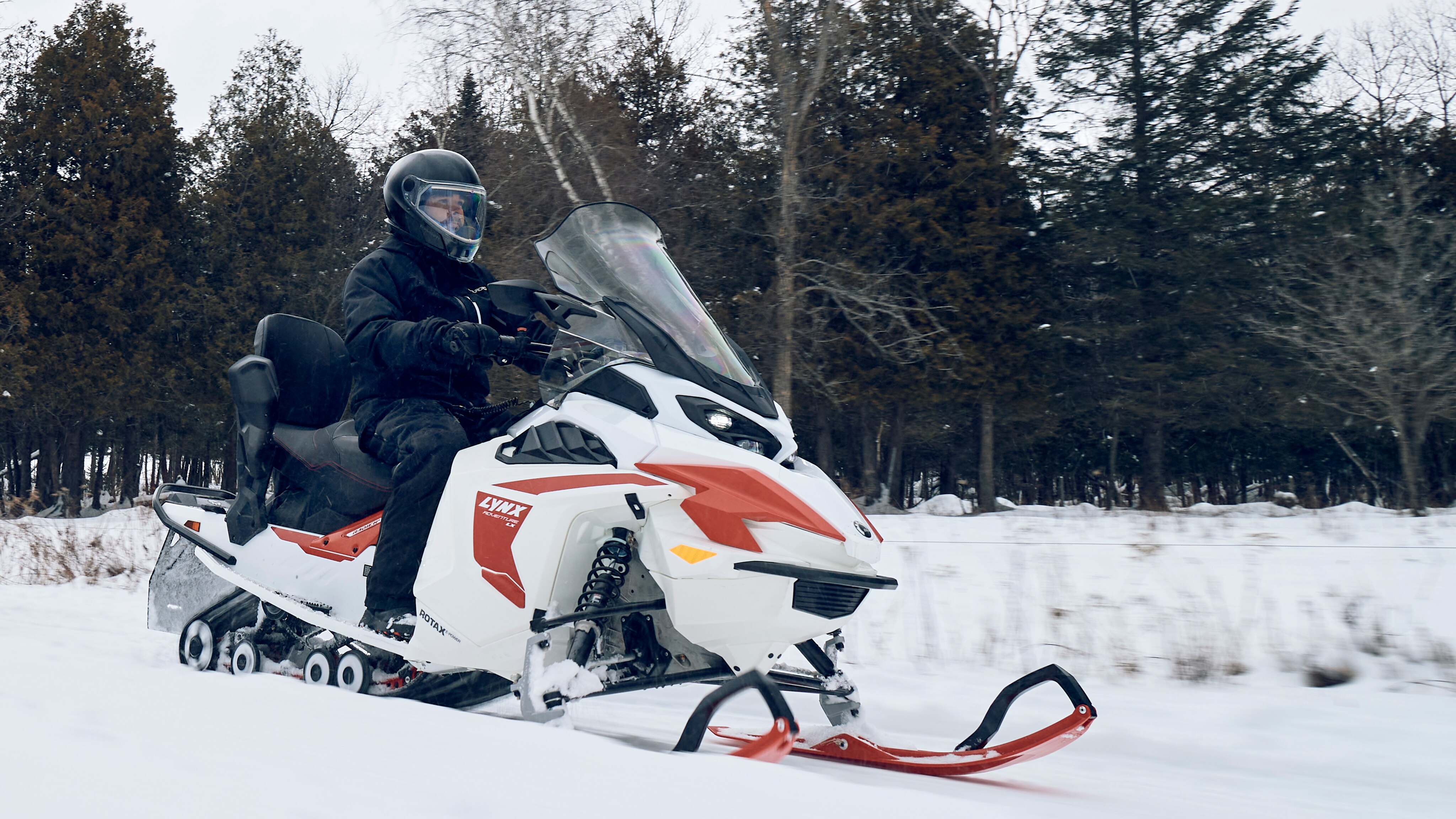 Mann som kjører Lynx elektrisk snøscooter på sti