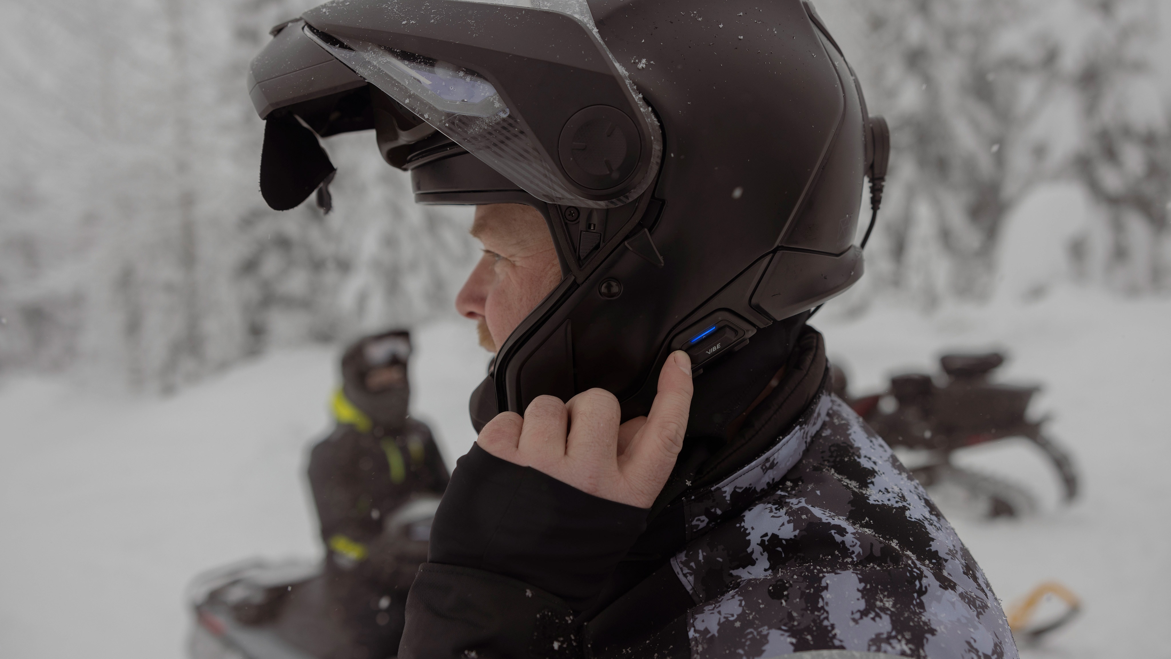 A snowmobile rider using the Vibe communication system on his helmet