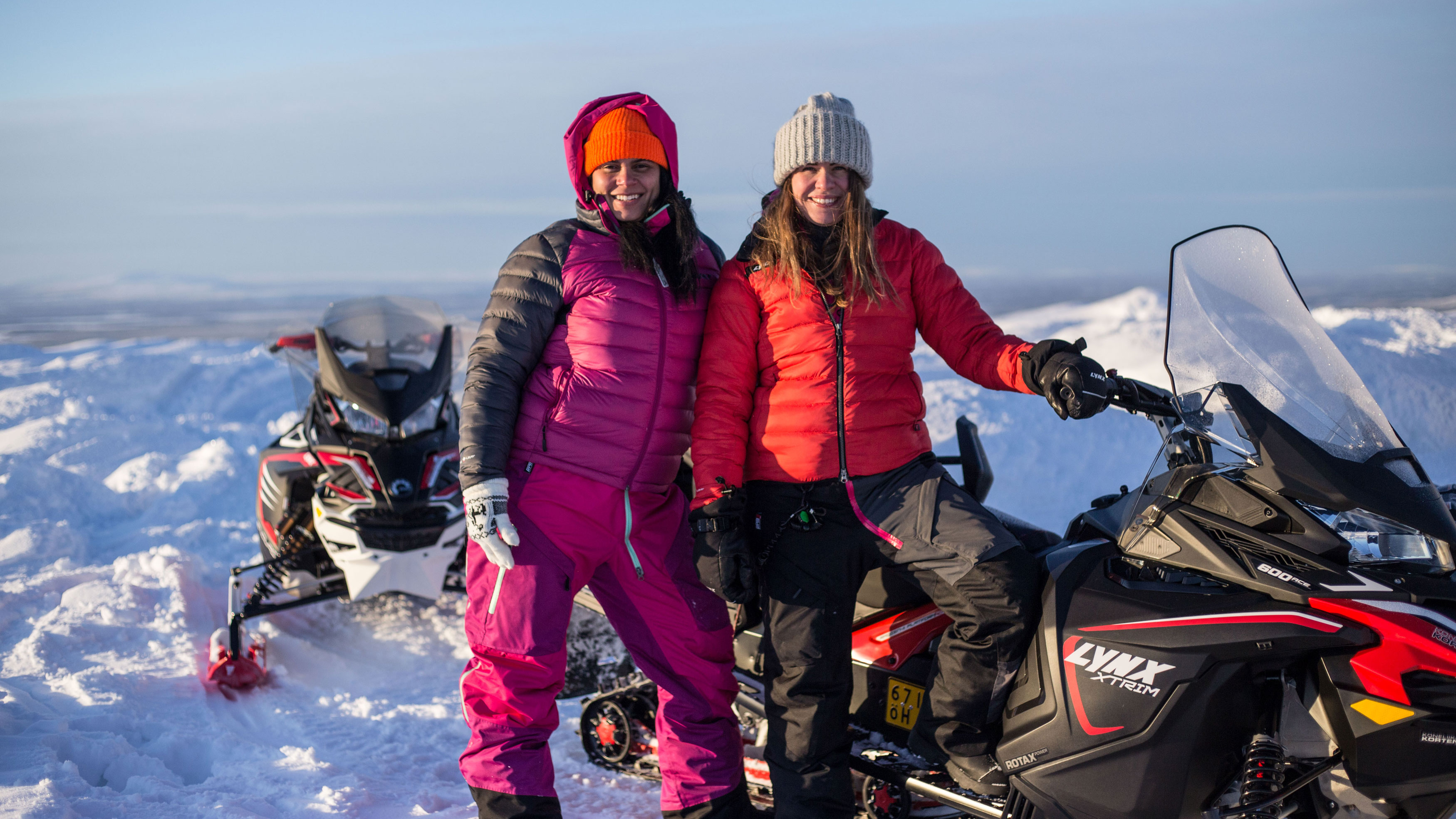 To kvinner tar en selfie og smiler på snøscootere