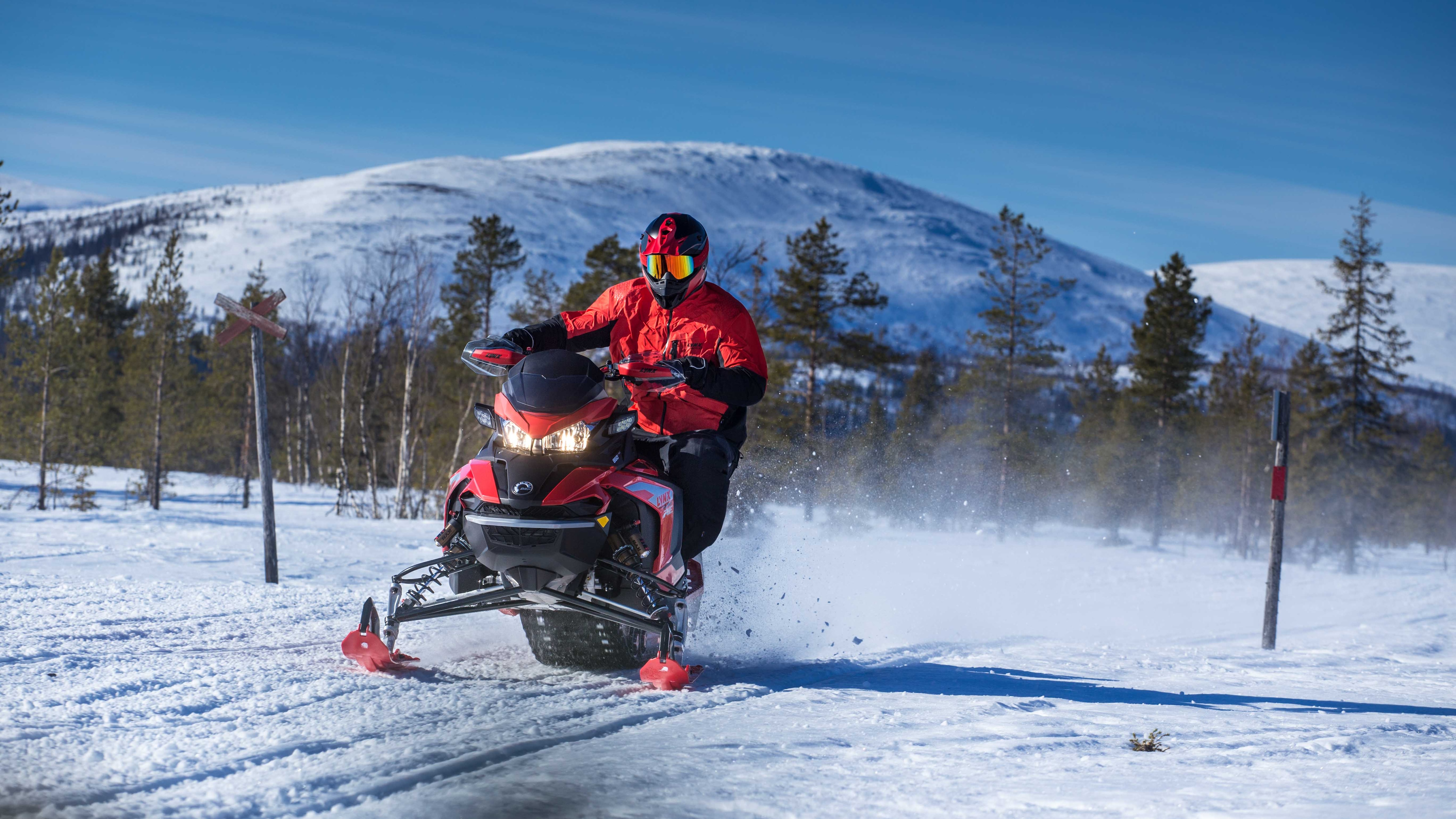 Football player Sami Hyypiä Lynx snowmobile riding on trail with mountain view