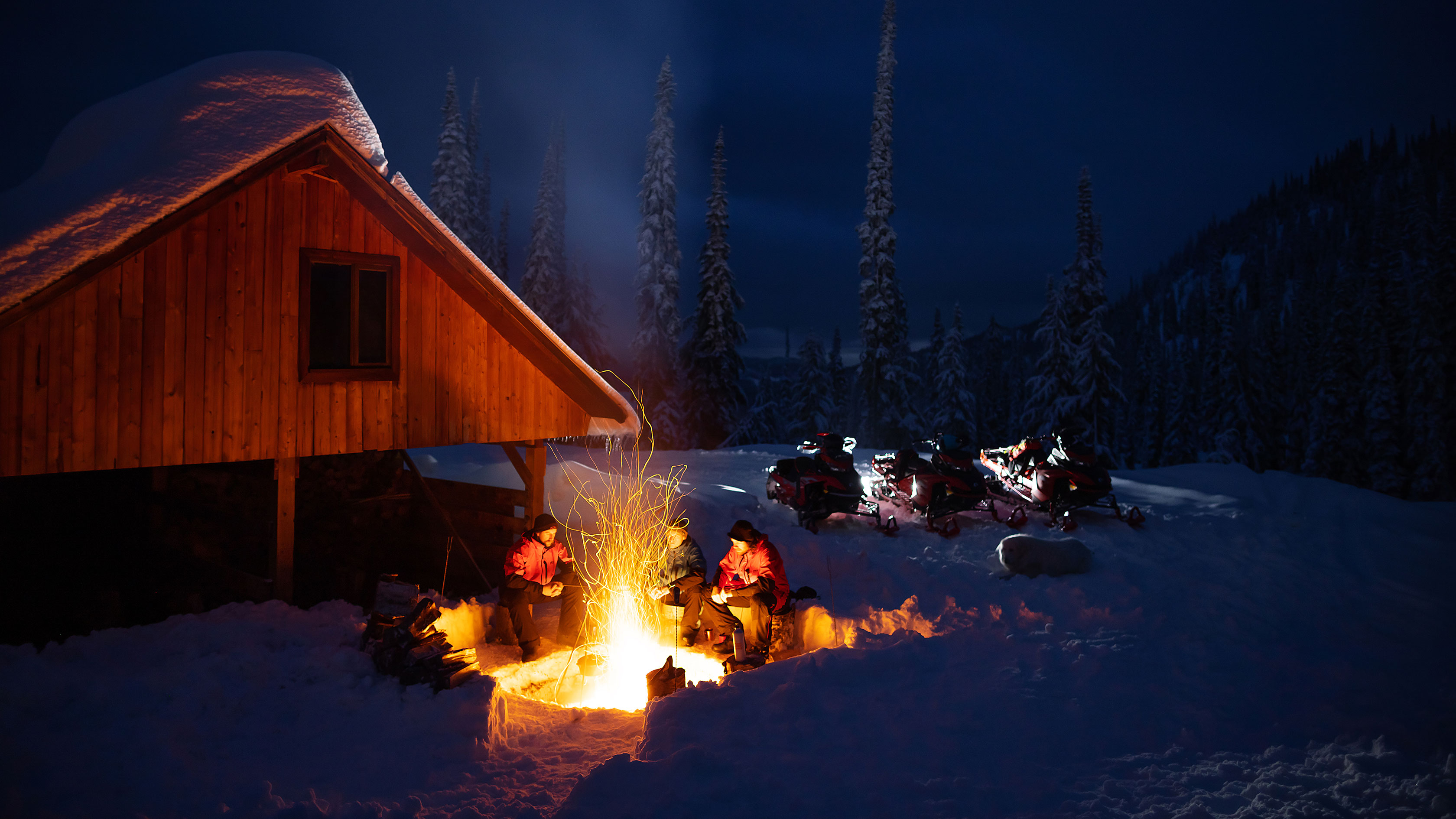 snowmobiles Lynx and riders near a campfire