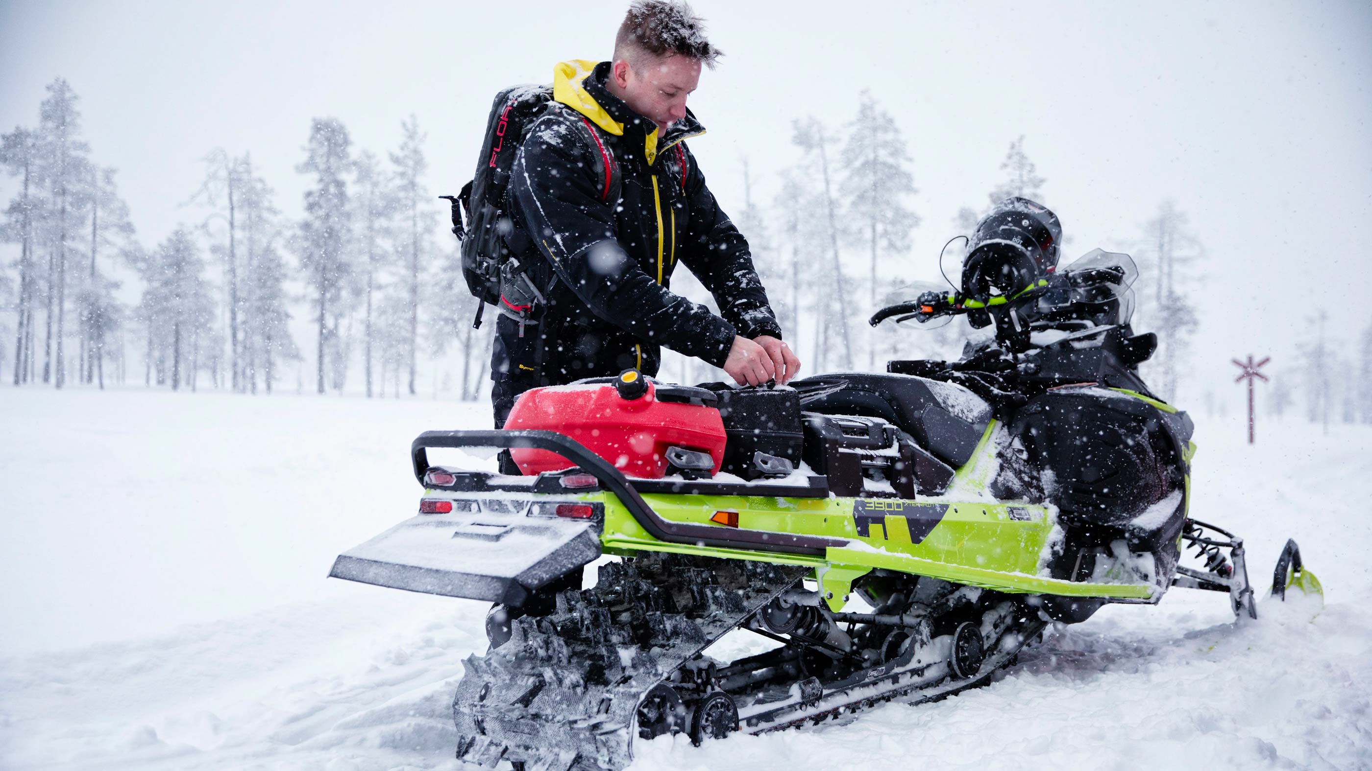 En mann åpner LinQ-posen som er montert på en Lynx Xterrain-snøscooter