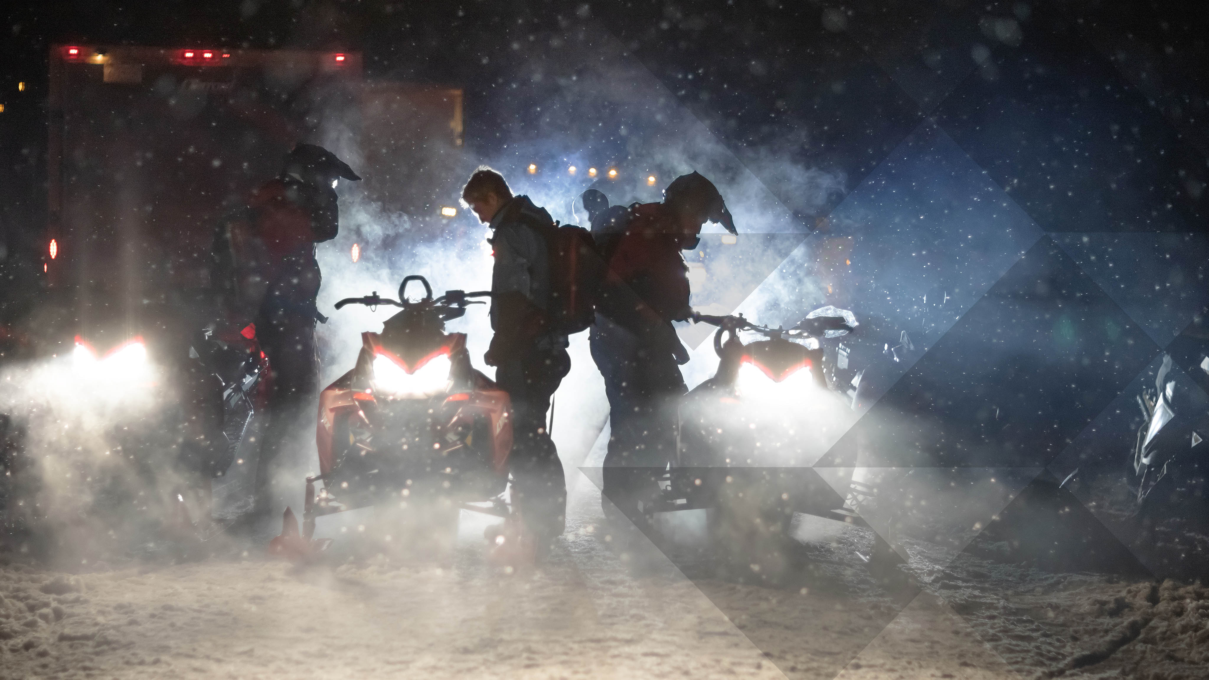 3 motoneigistes préparant une promenade nocturne en motoneige