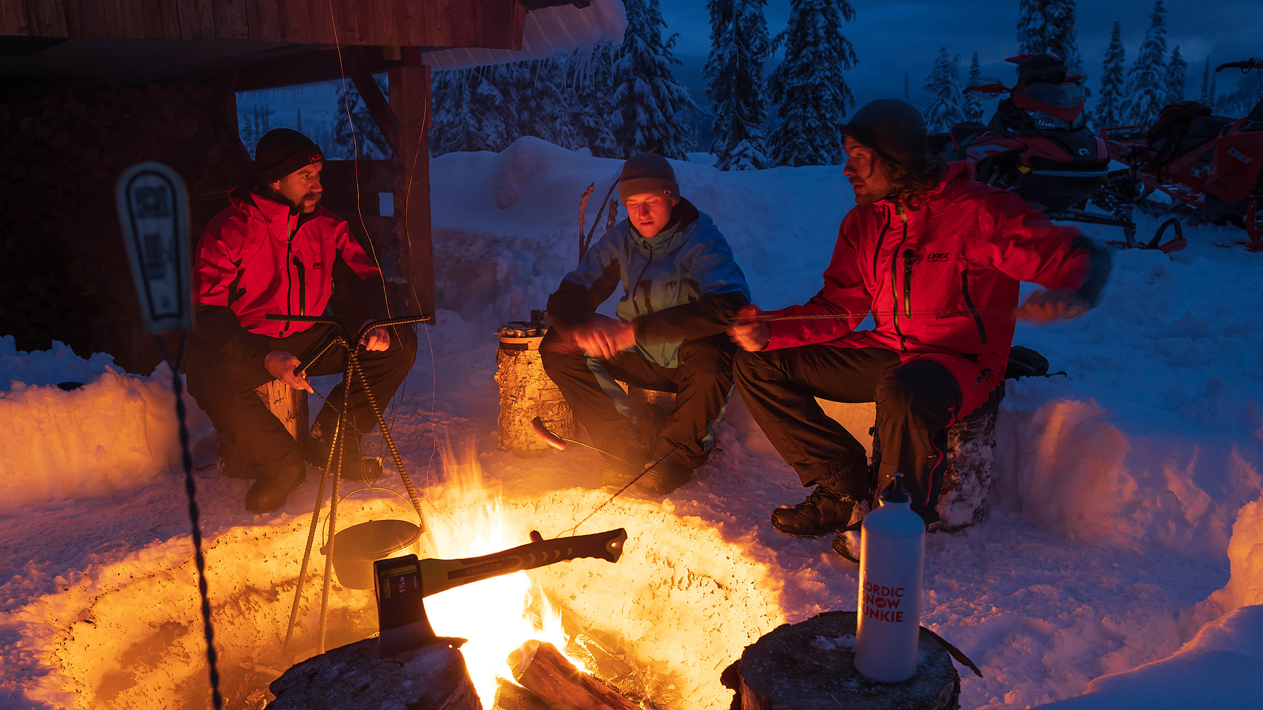 3 riders around the fire after their snowmobile ride
