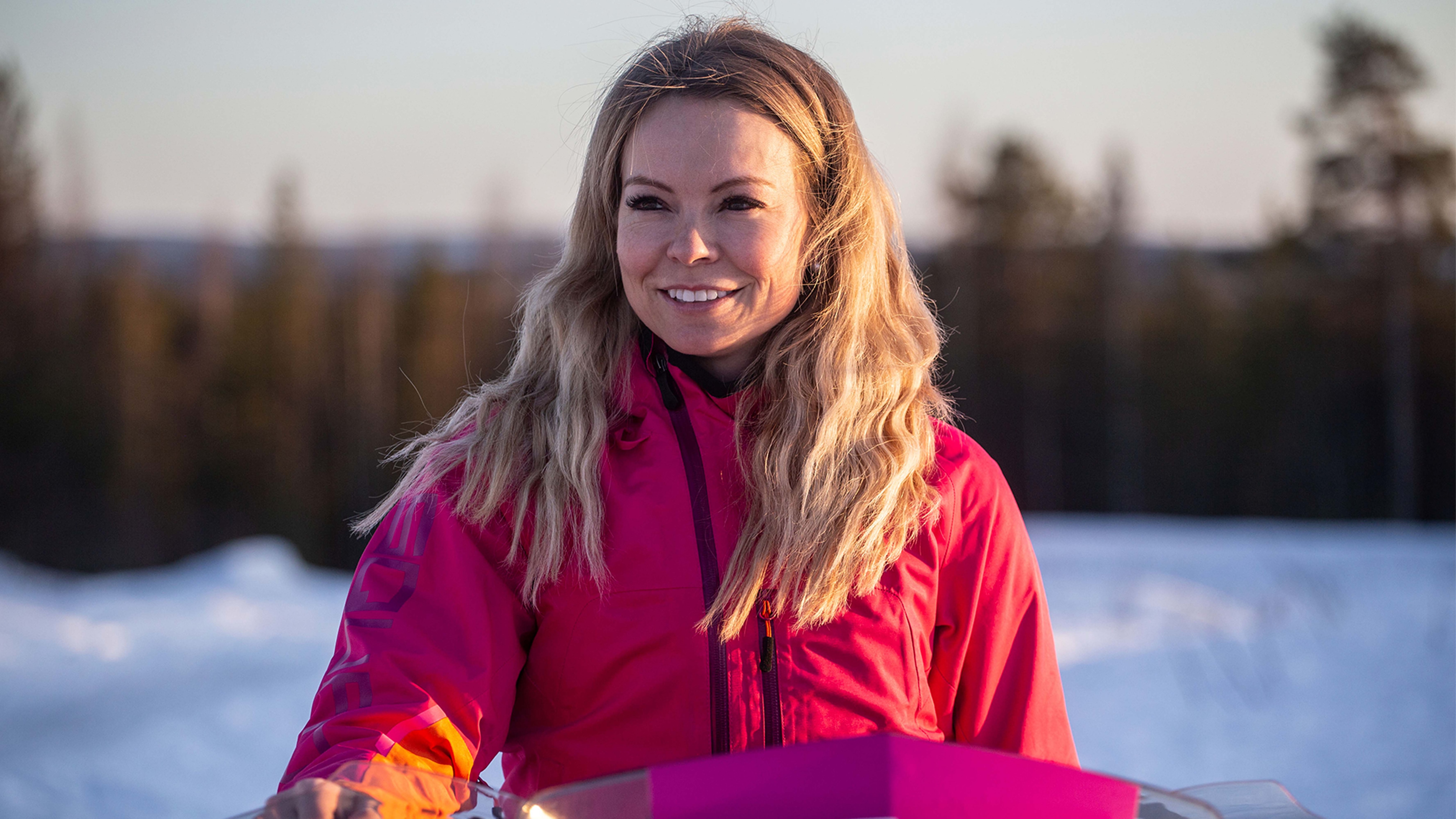 A women is sitting on a snowmobile with a smile