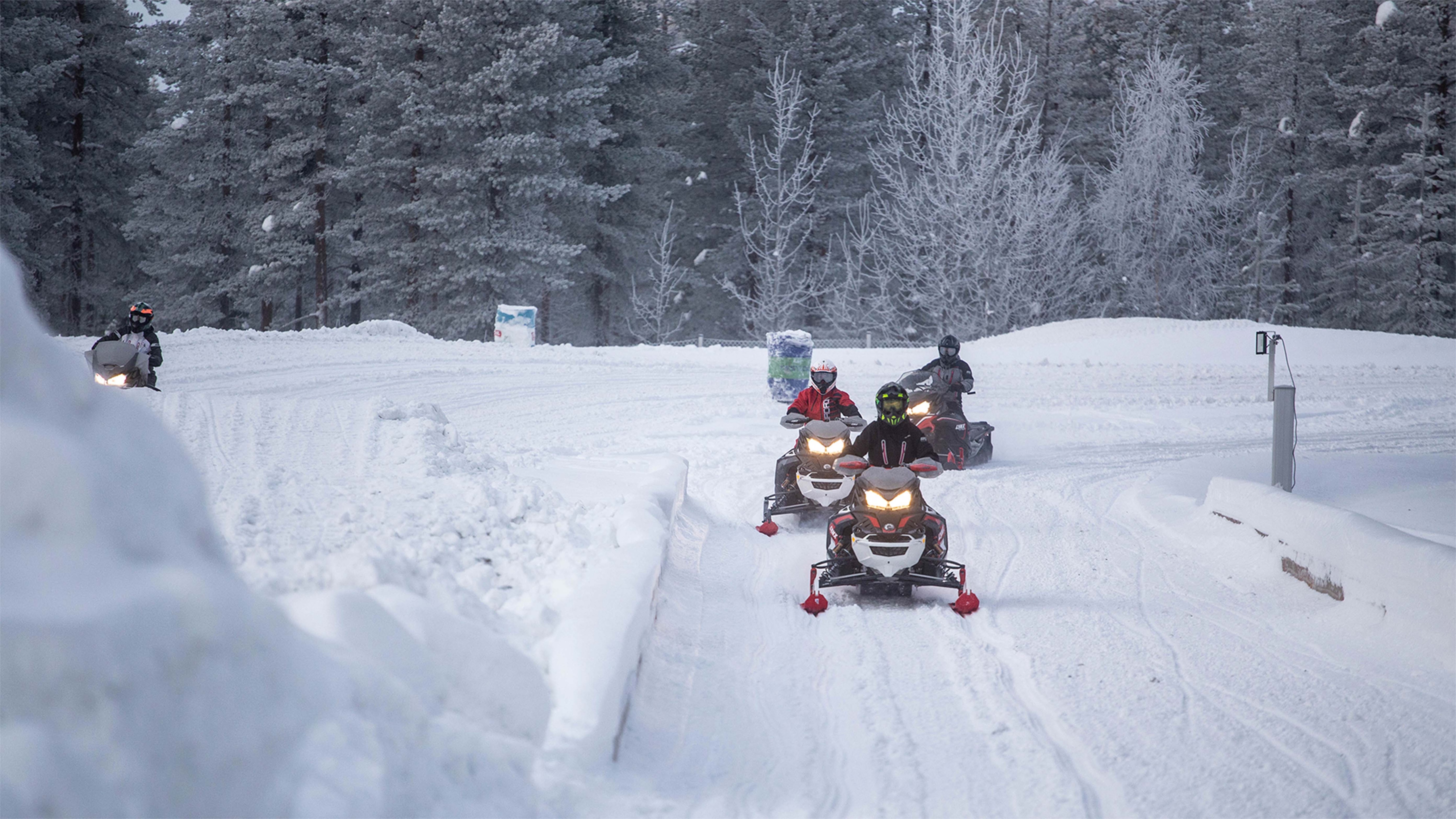 Four snowmobiles riding in a group