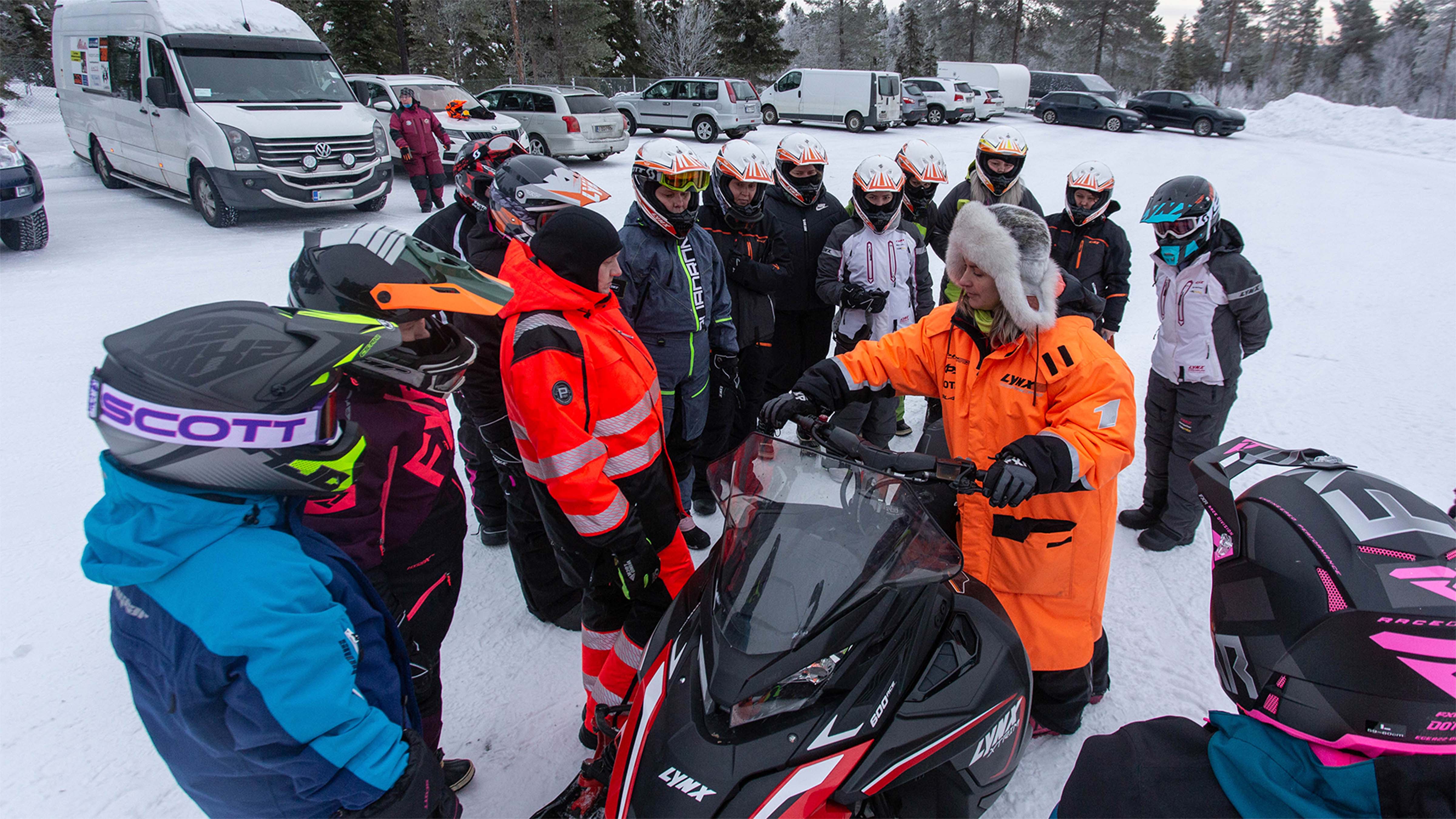 Instructor giving a guidance for trainees about snowmobile controls