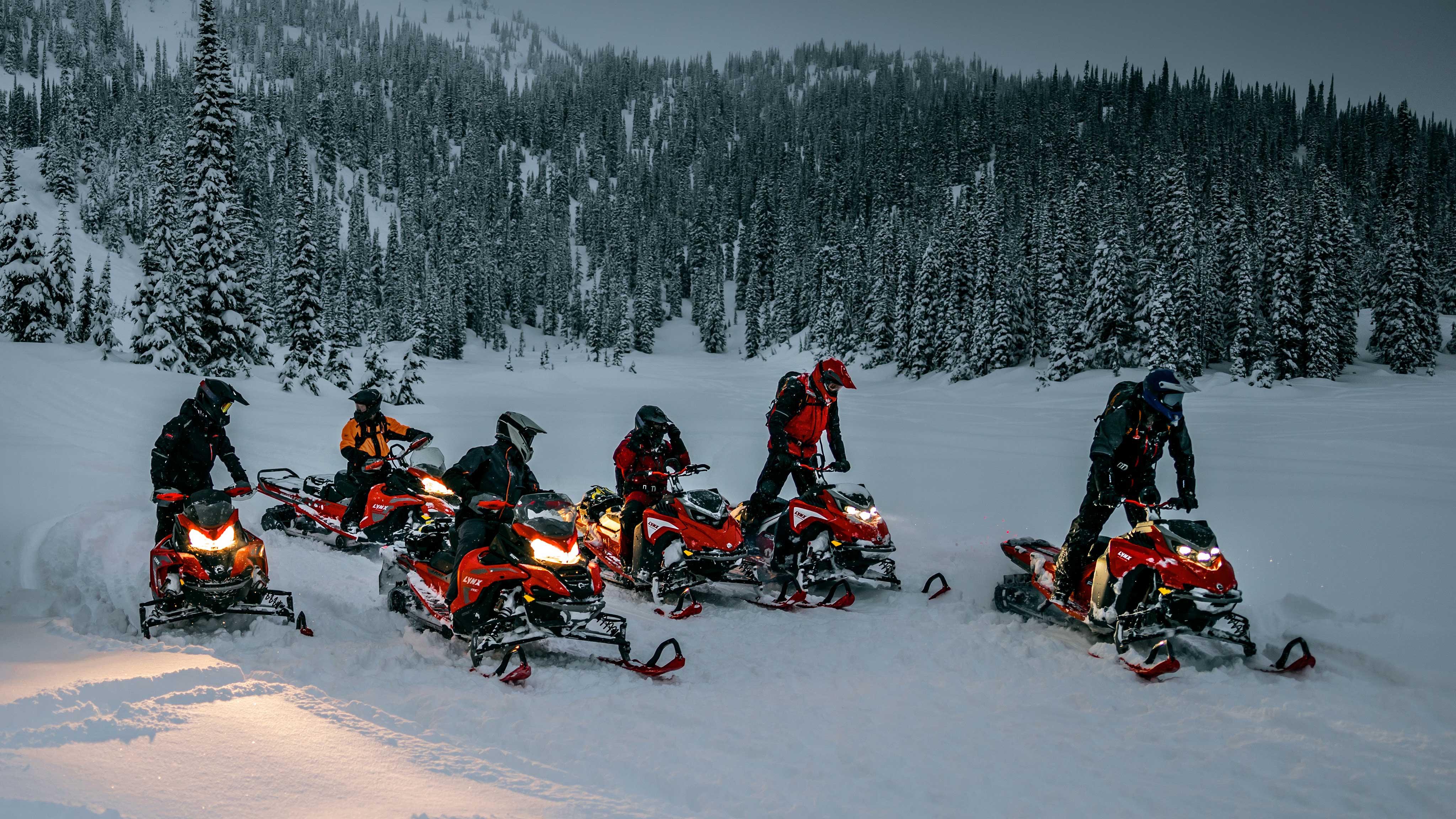 Famille de motoneigiste profitant de la neige avec leurs motoneiges Lynx