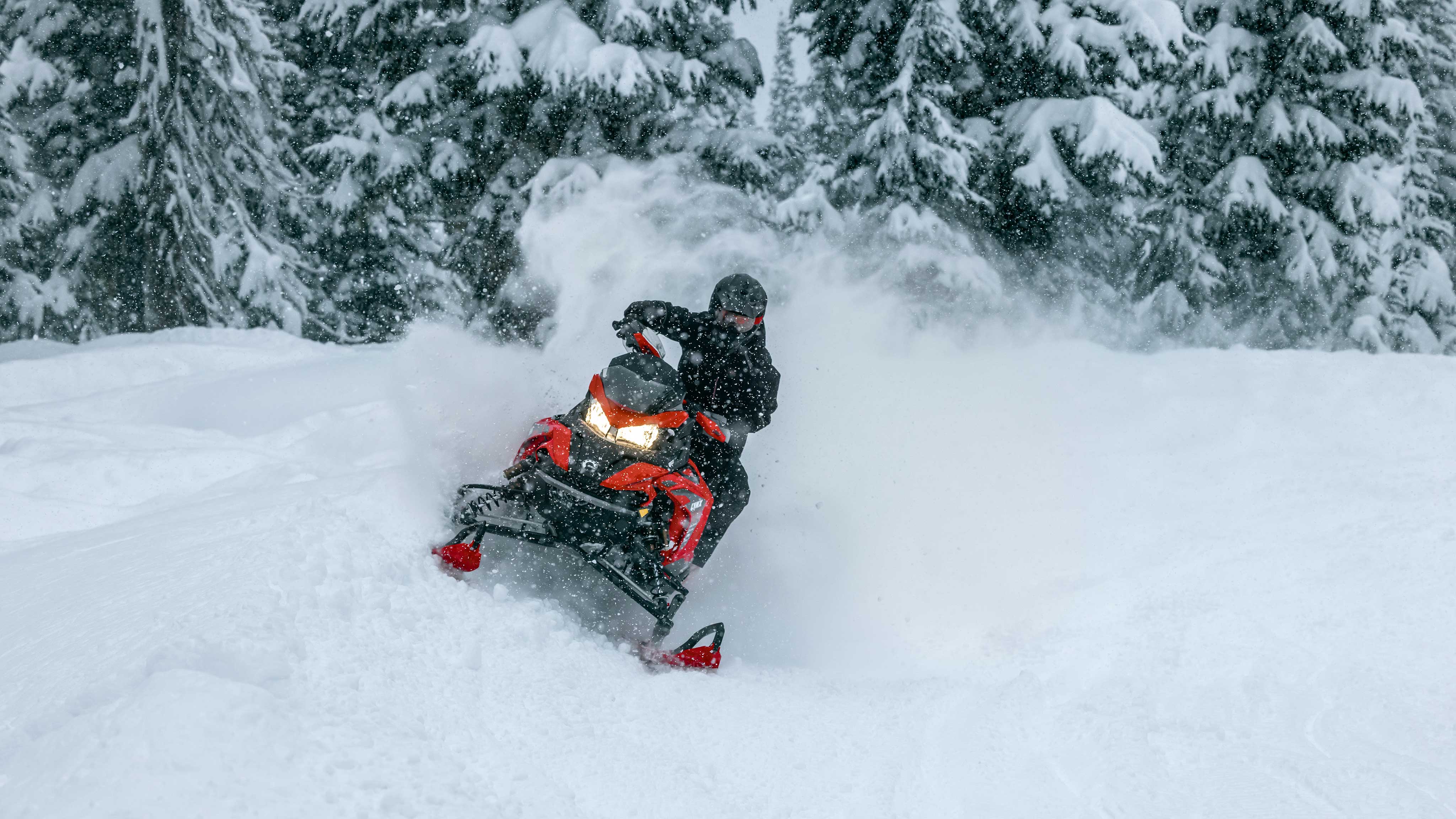 Single rider taking his 2023 Lynx snowmobile for a ride in a snowy forest