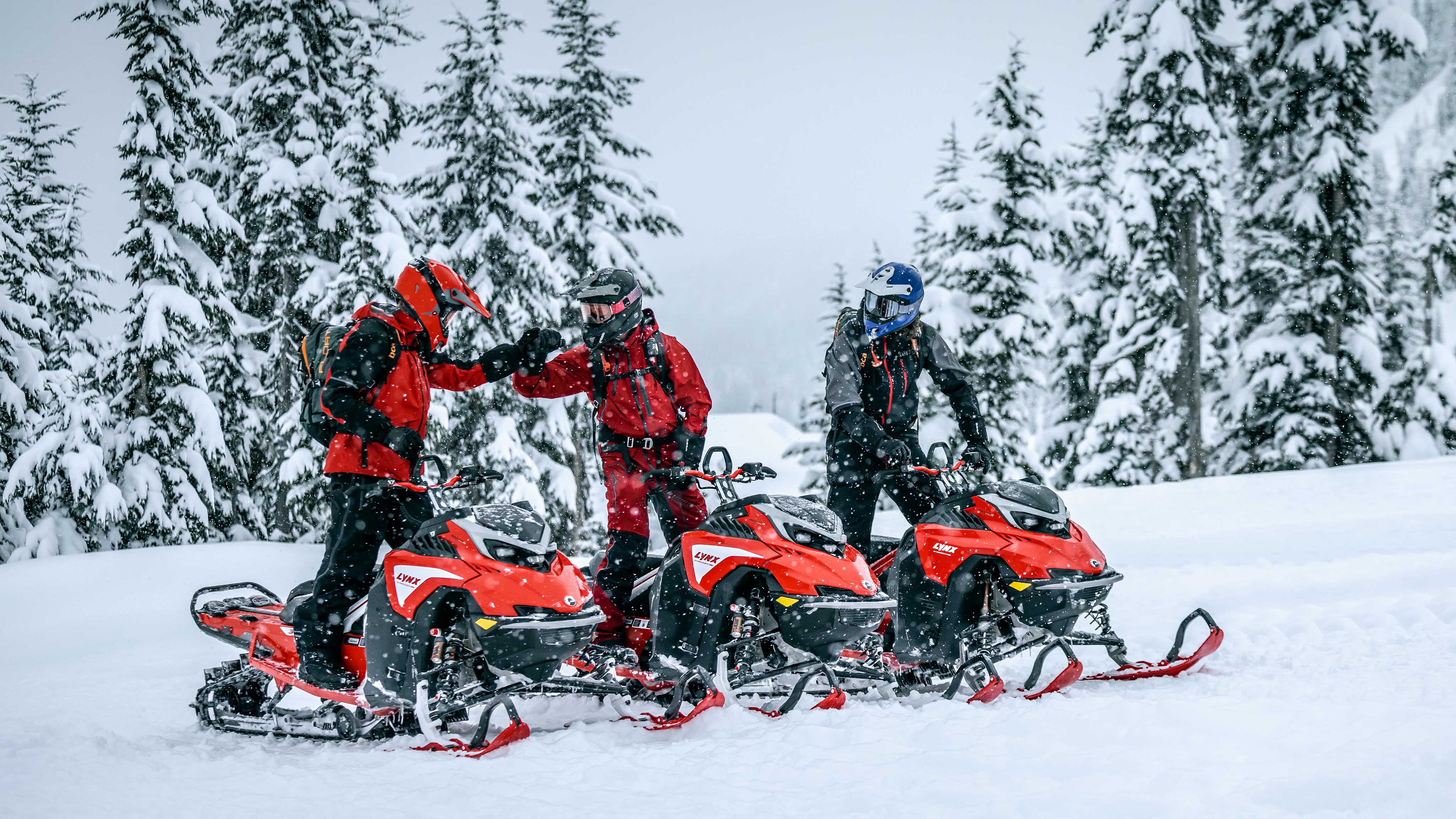 Friends taking a short break from riding their Lynx snowmobile