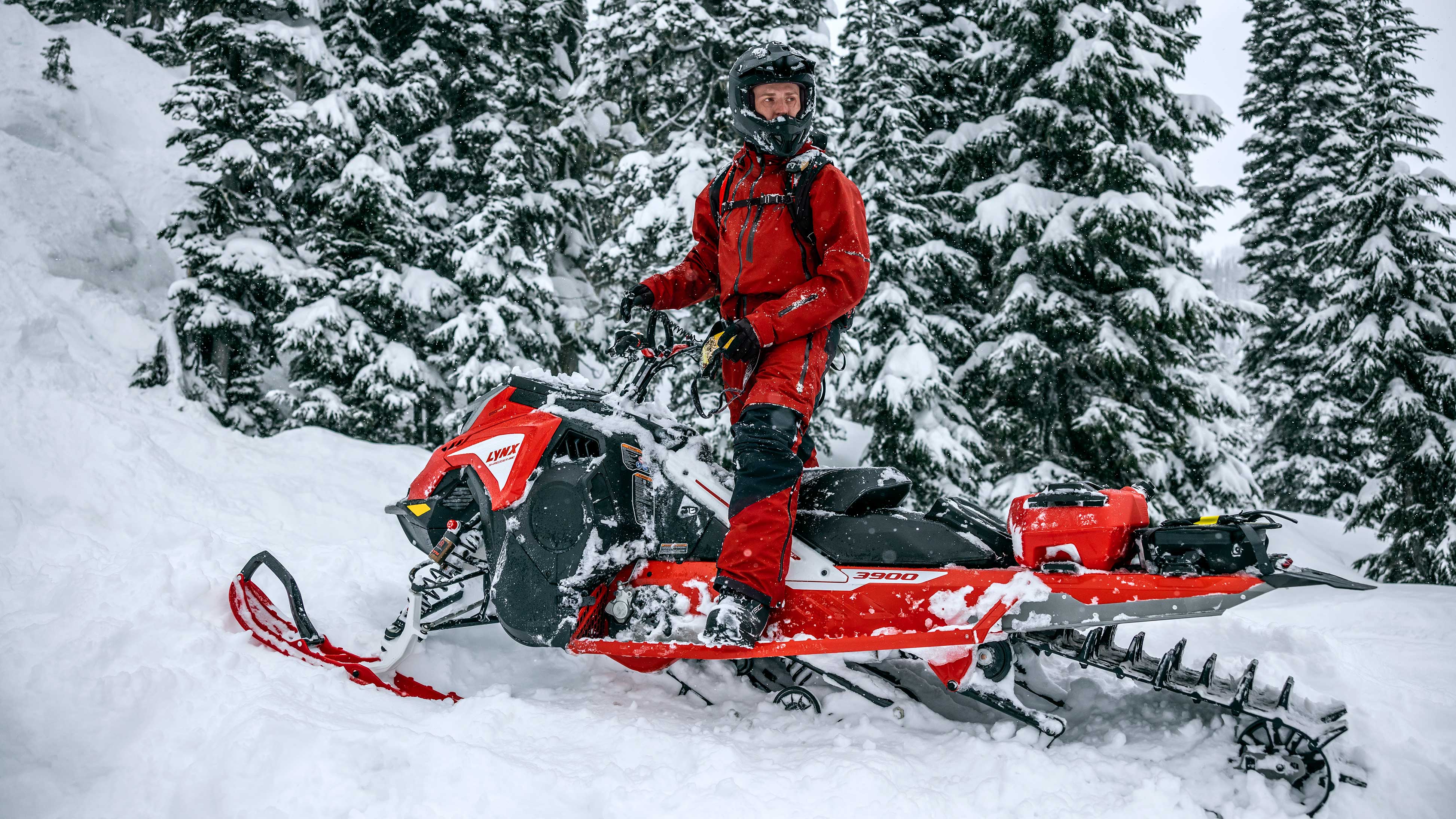 Rider standing on their fully equipped Lynx snowmobile looking around