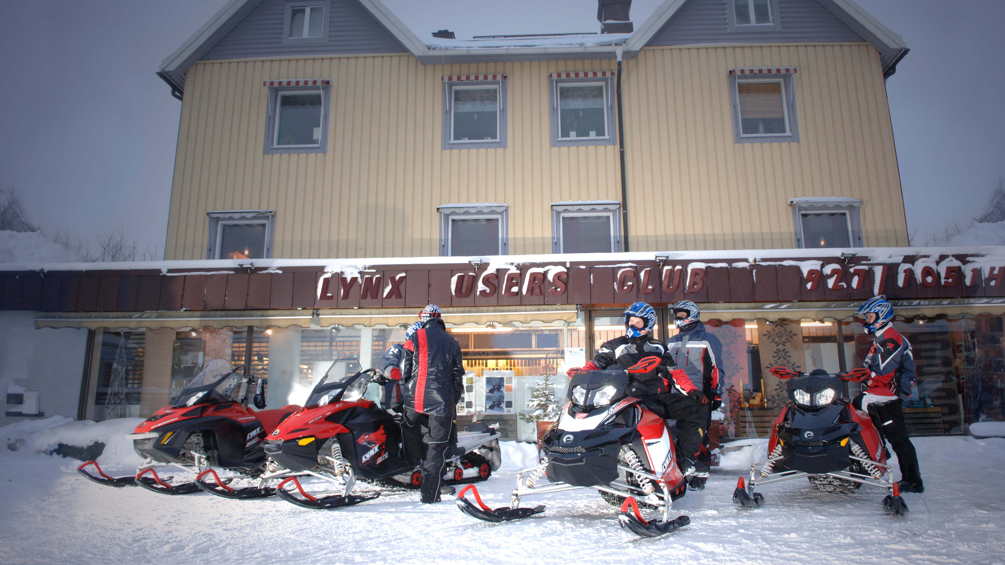 Four snowmobiles at parking lot of a shop