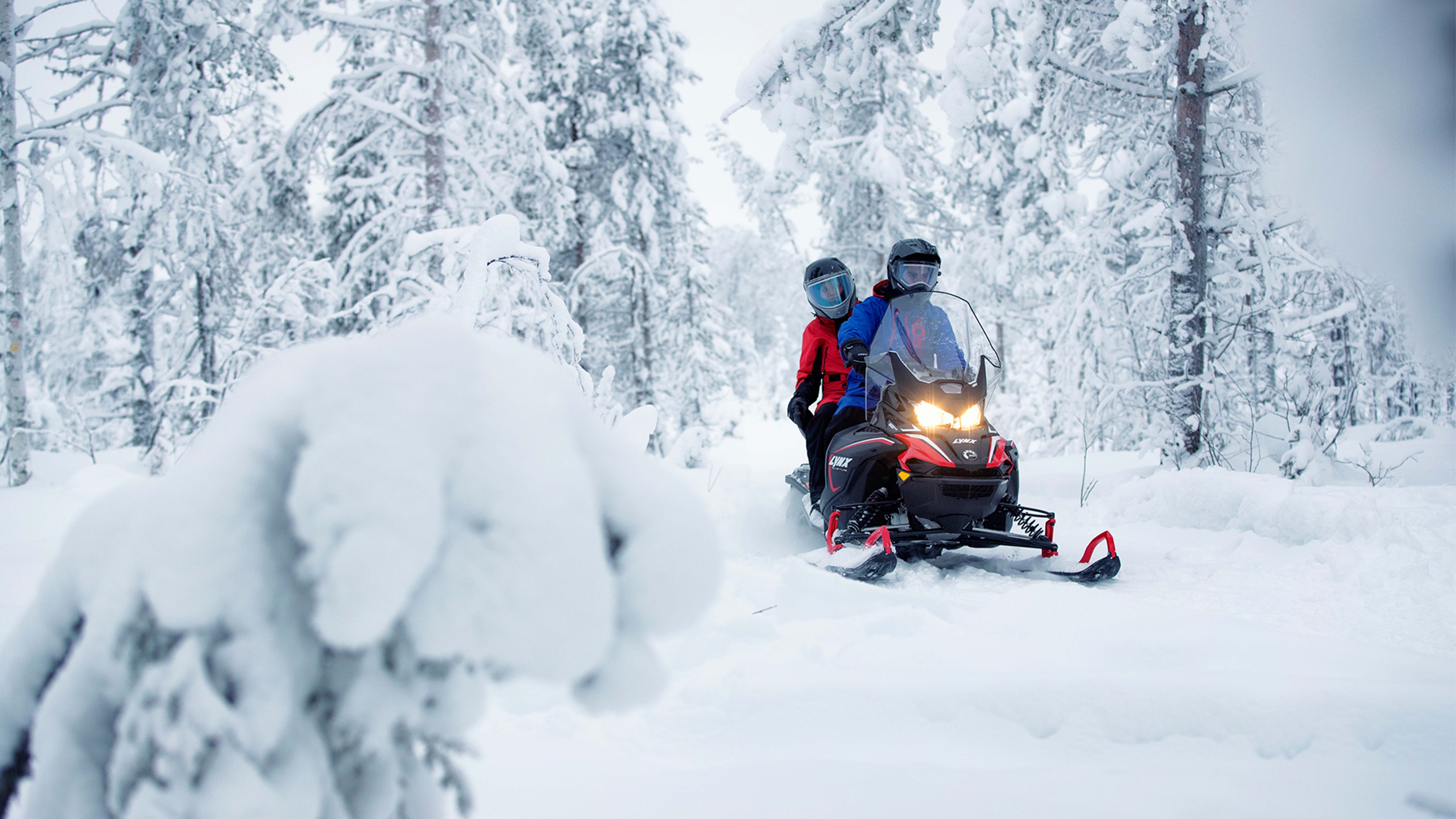 A couple riding with Lynx Adventure LX snowmobile riding on trail