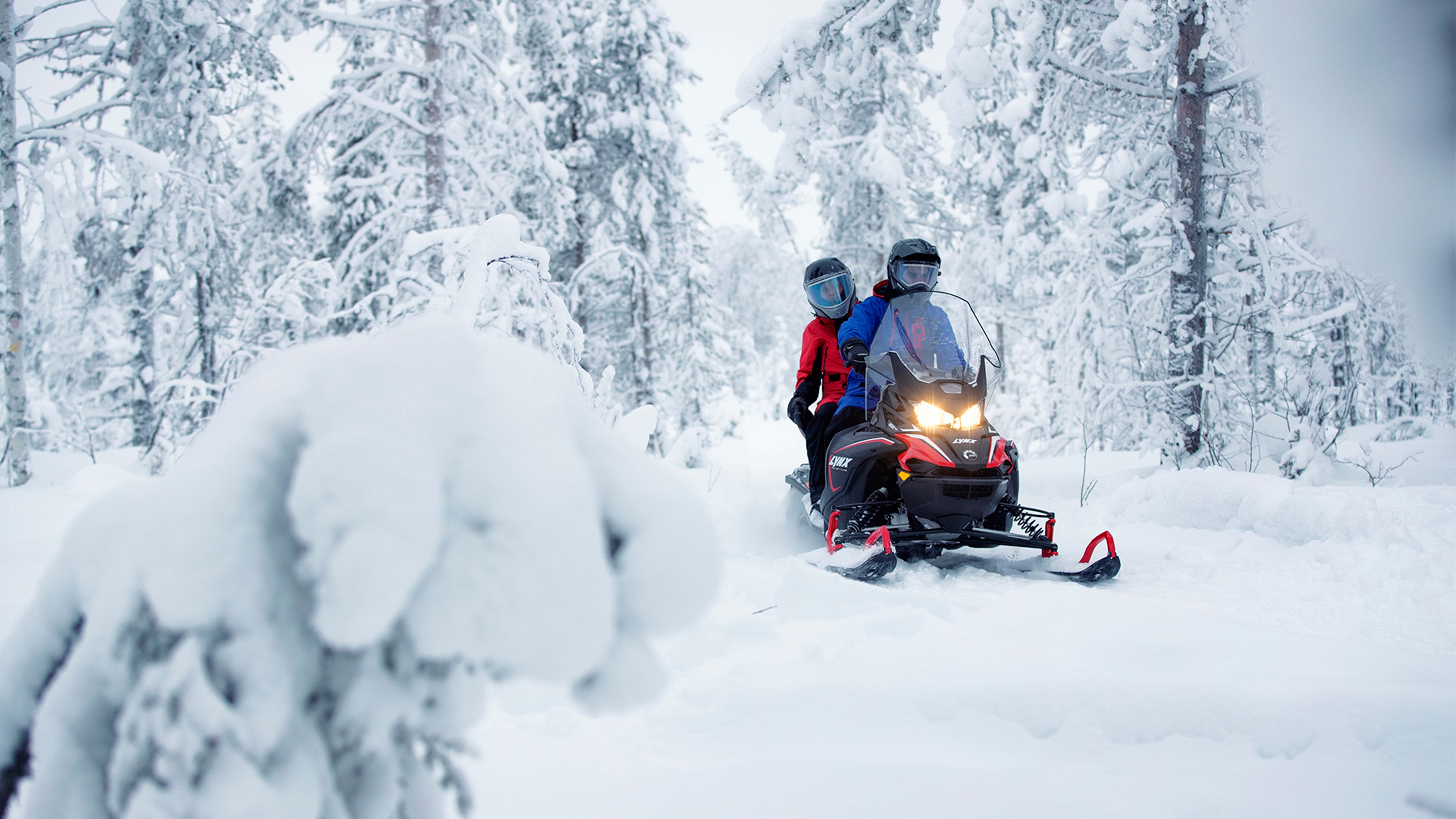 Ett par som åker med en Lynx Adventure LX snöskoter på led