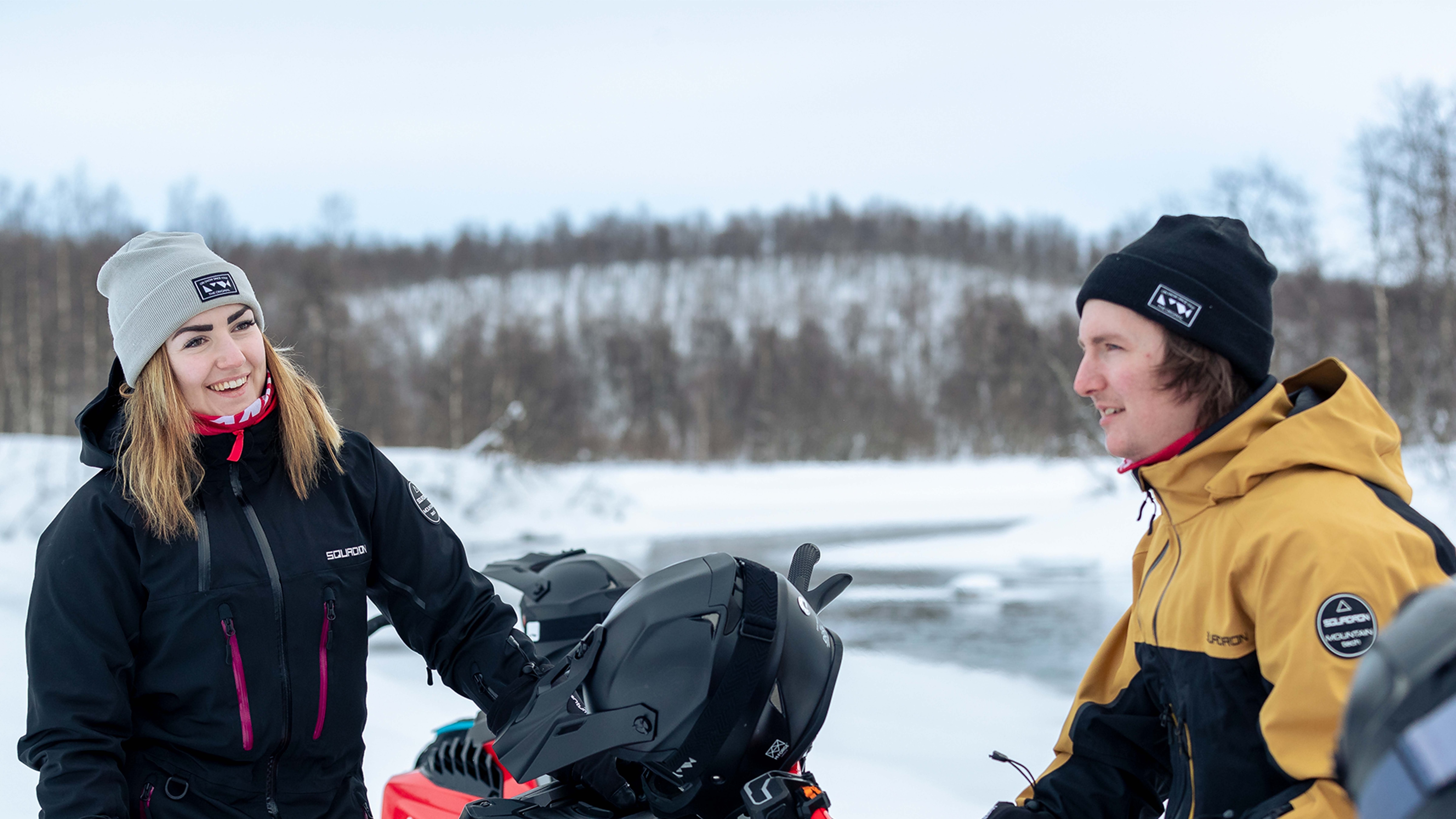 Couple laughing on snowmobiles
