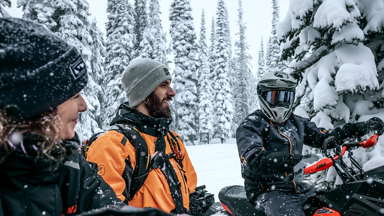 Three riders having a break on snowmobiles