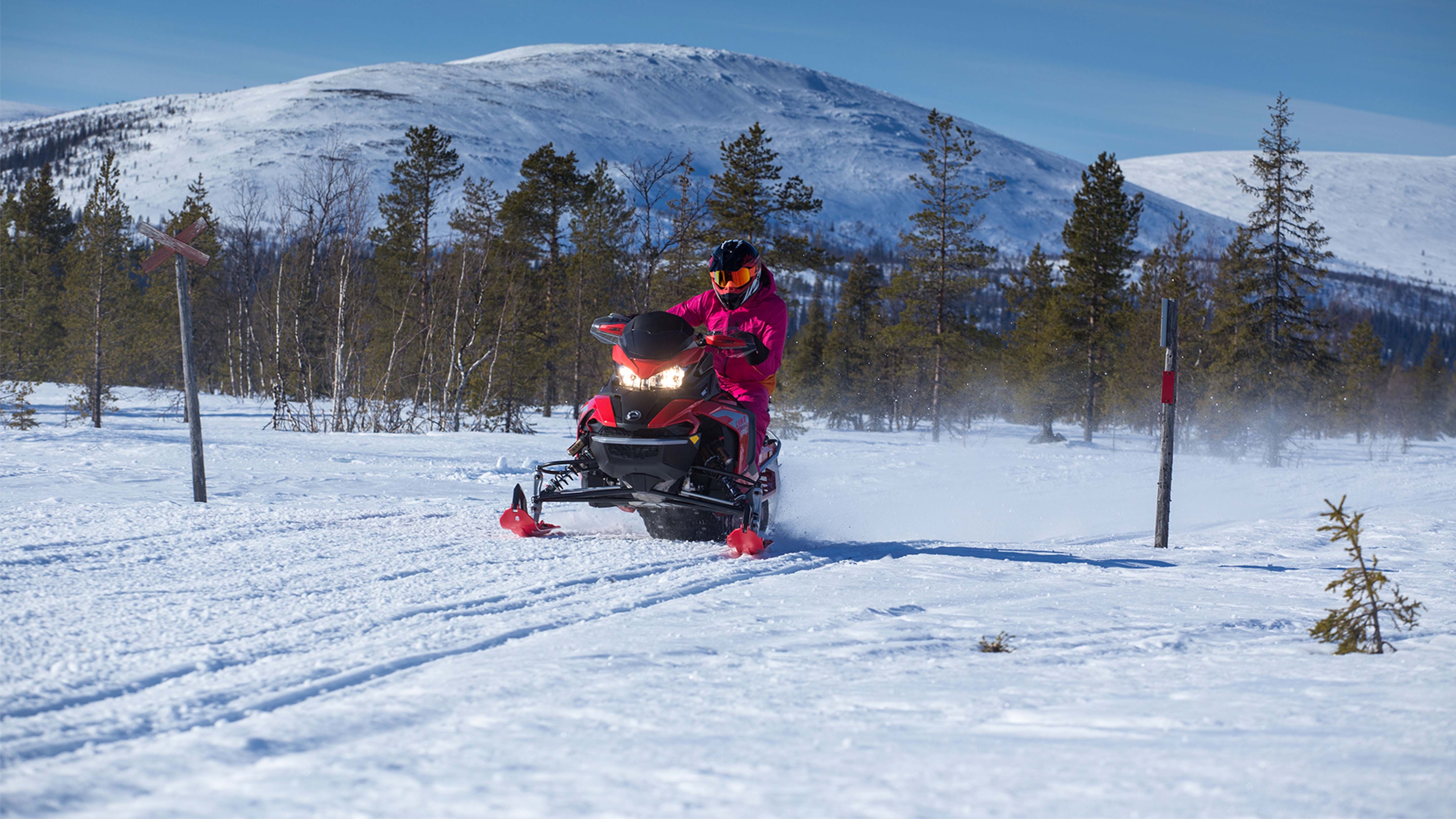 Emma Kimiläinen kjører på en fjellsti med vid utsikt fra sin Lynx Rave RE snøscooter