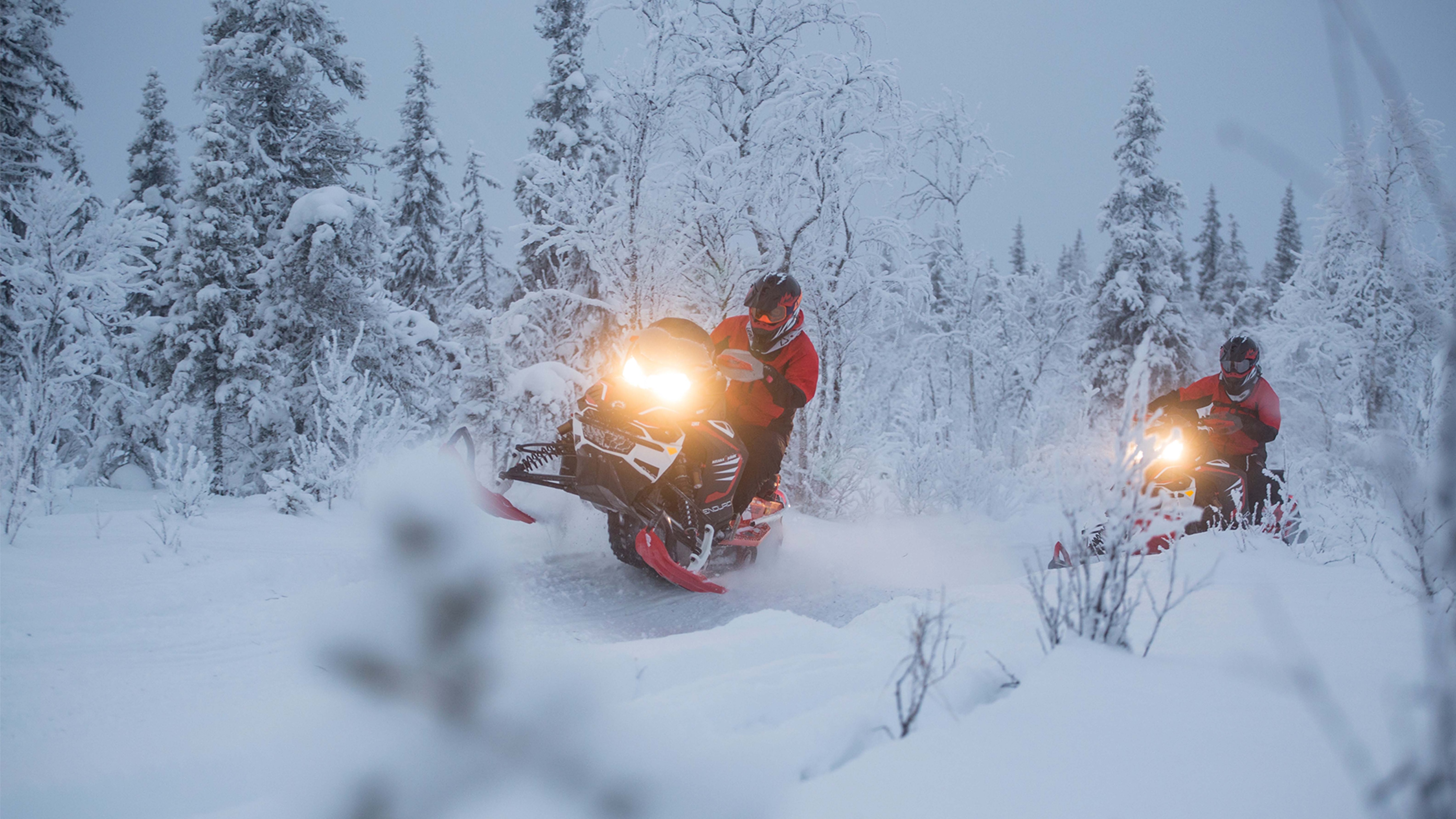 To Lynx Rave Enduro-snøscootere akselererer i en løype