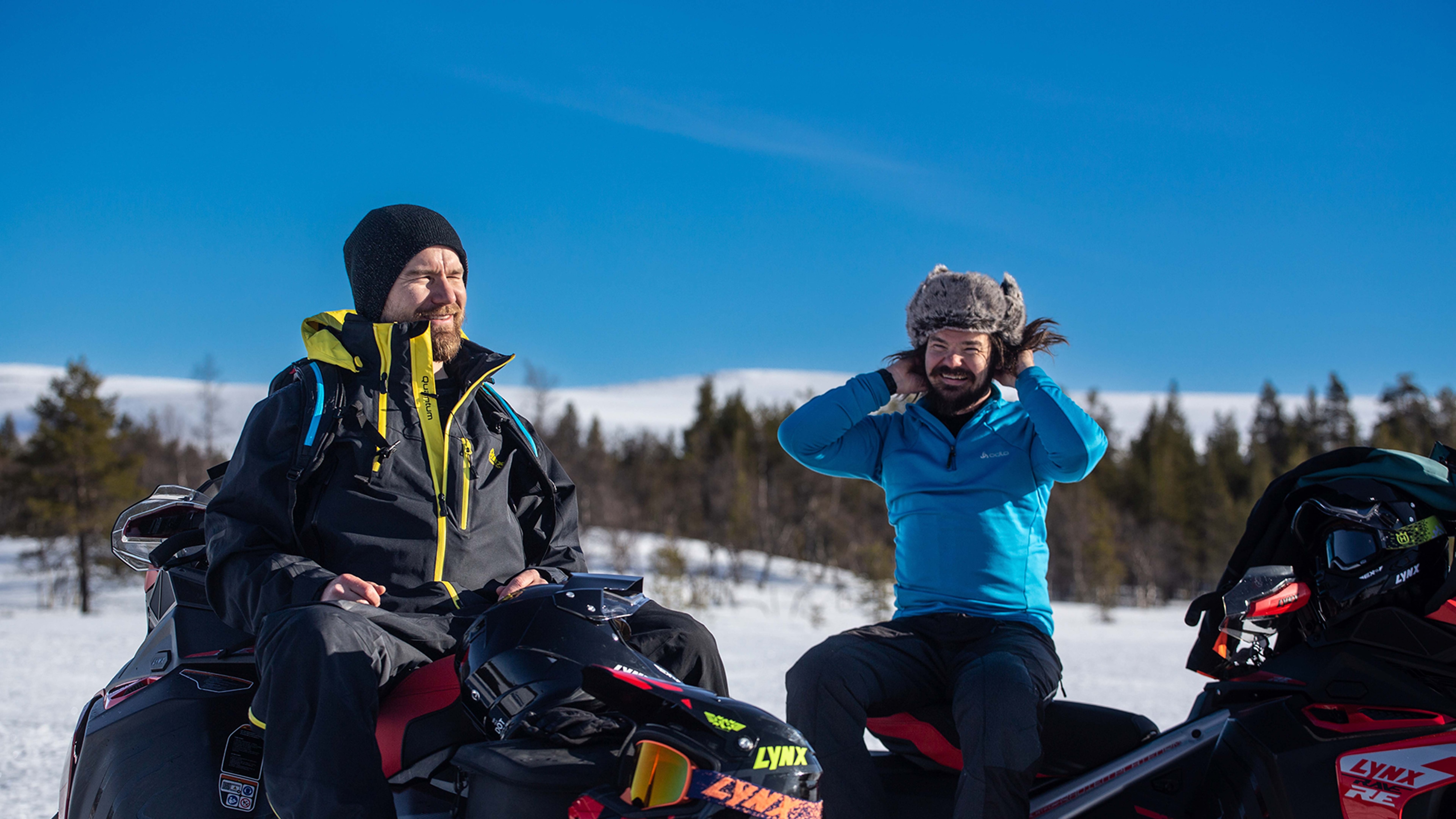 Janne Kaperi and Kaitsu Rinkinen from Biisonimafia chatting and laughing on snowmobiles