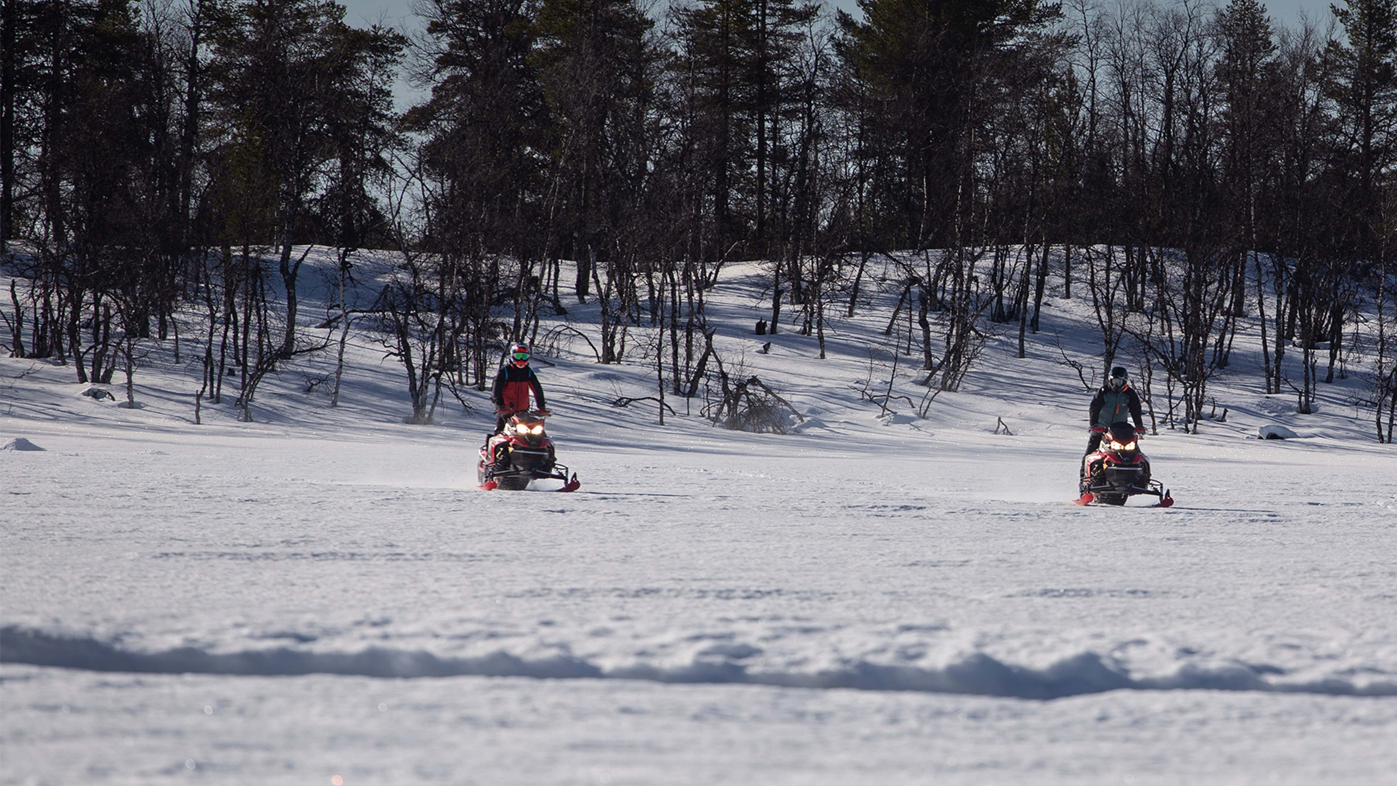 Two snowmobiles ride on lake