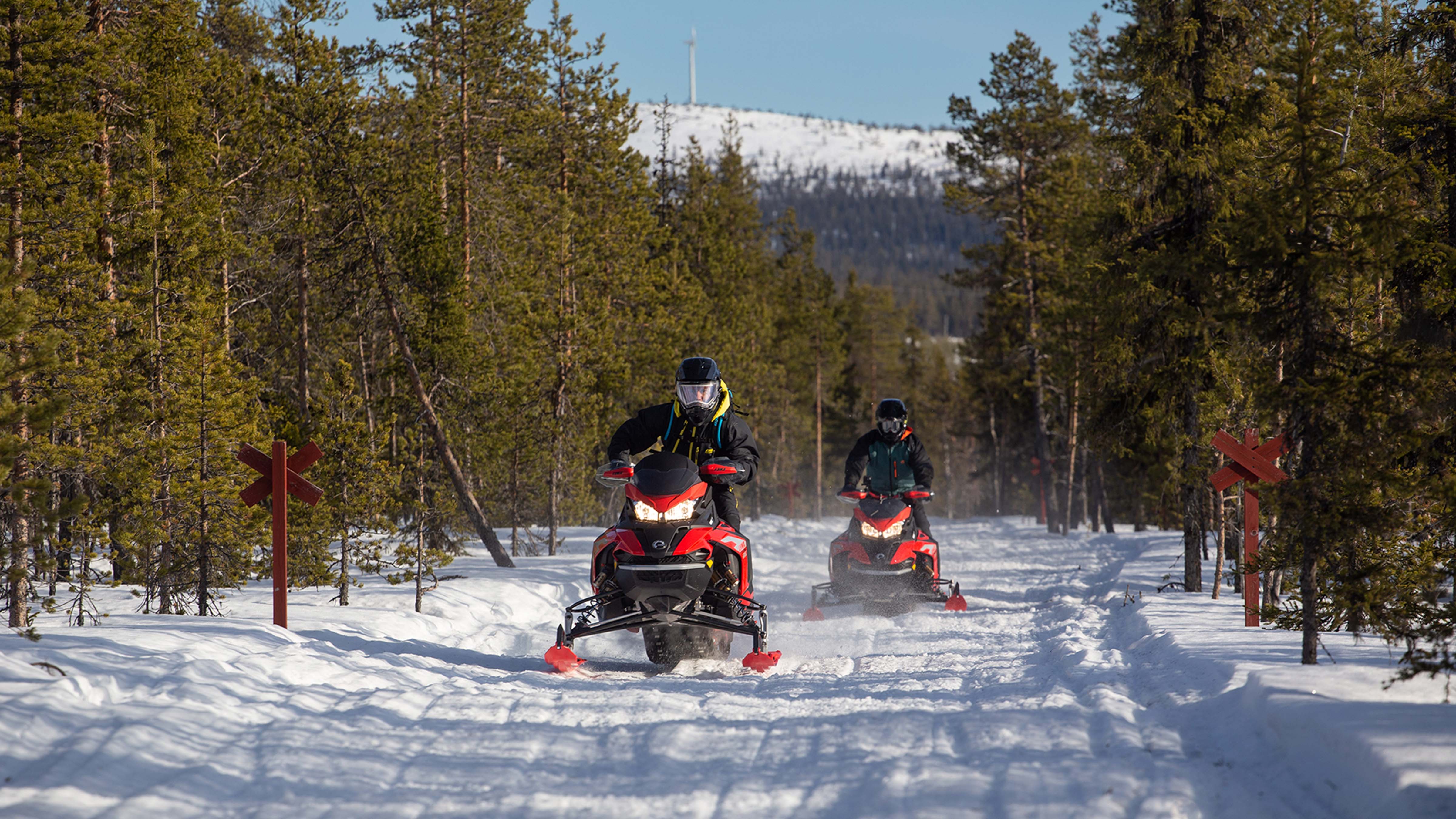 Two snowmobiles are riding on the bumpy trail