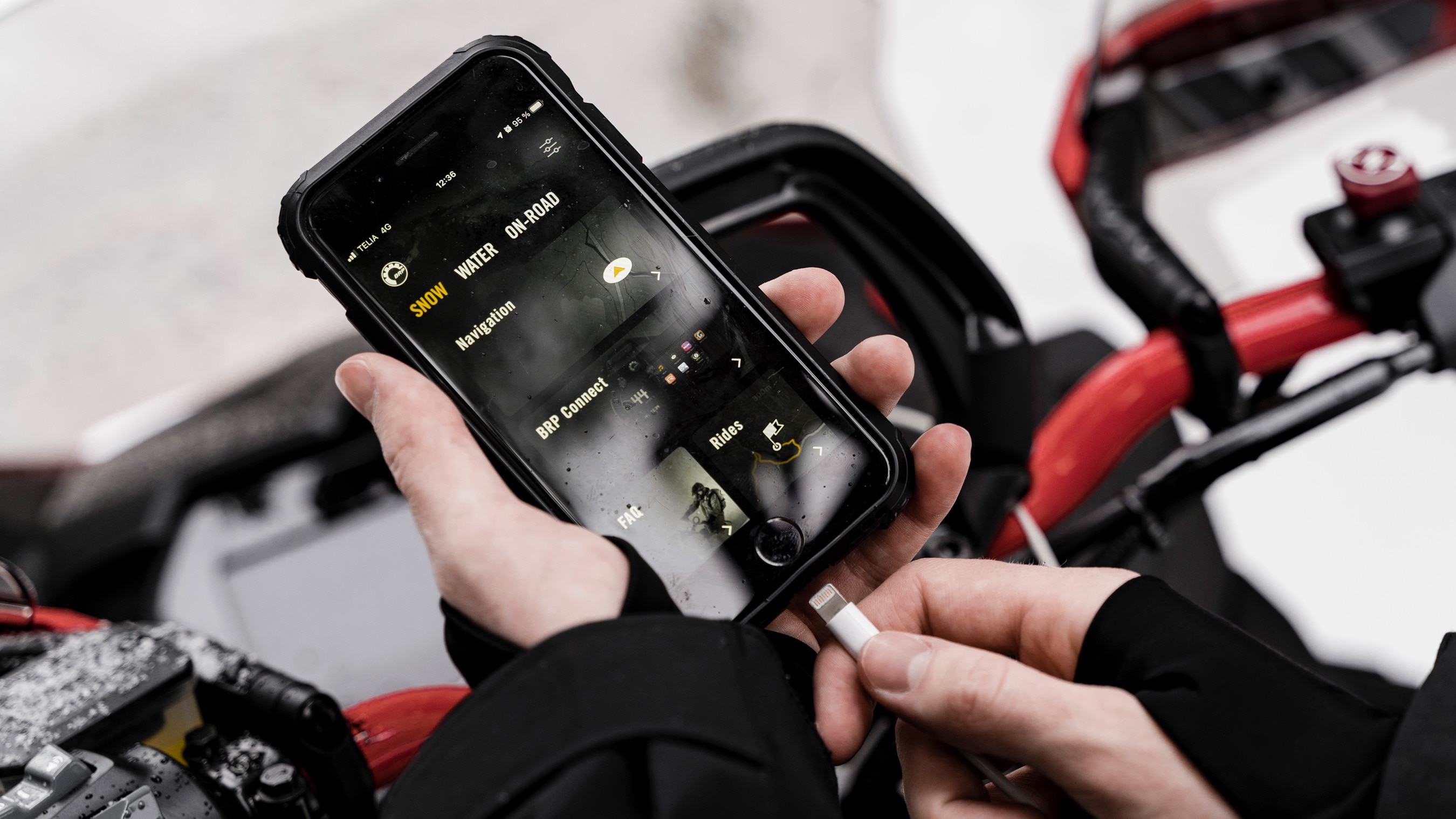Person using the BRP GO! App next to a Lynx sled
