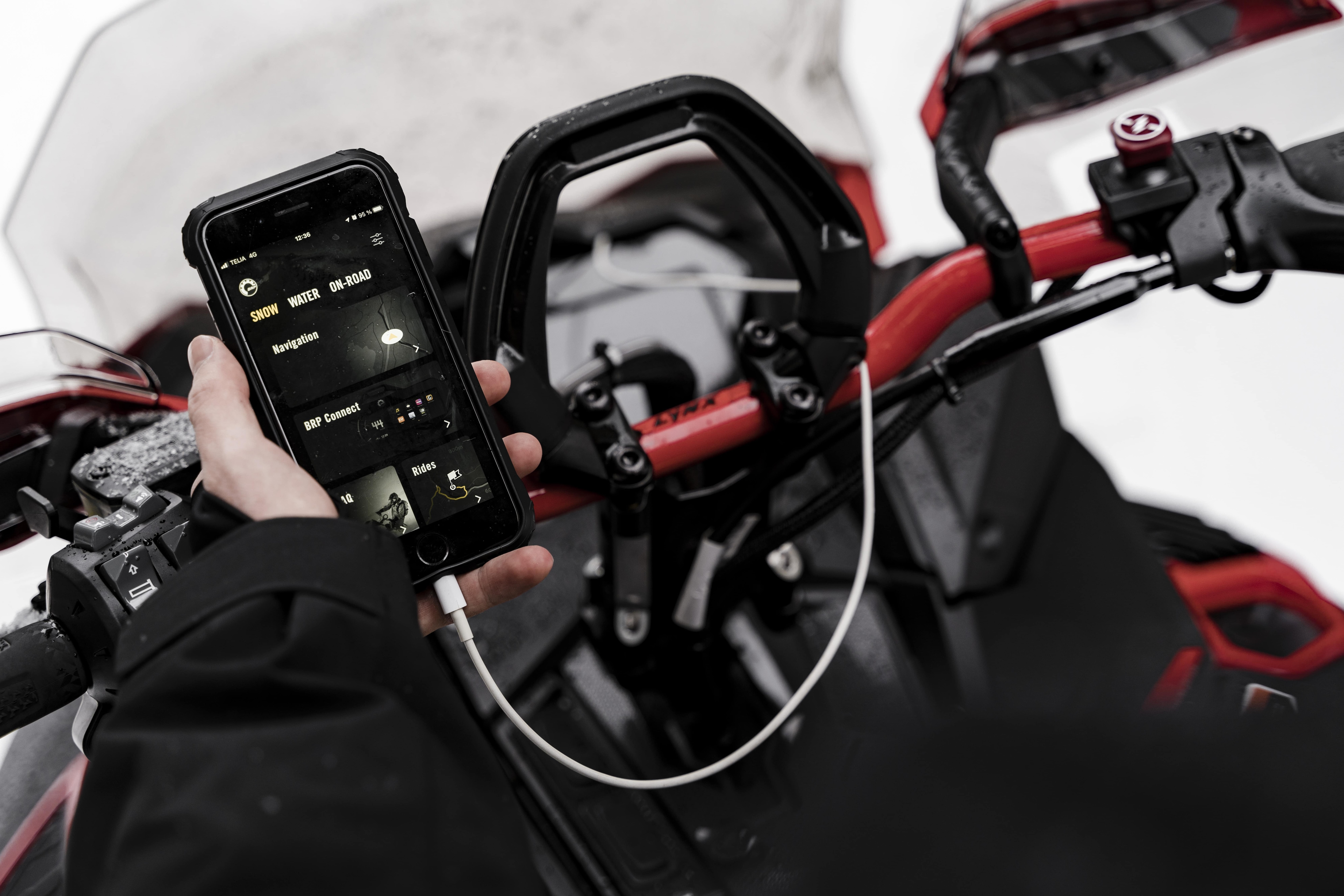 BRP GO! app on a phone near a Lynx snowmobile