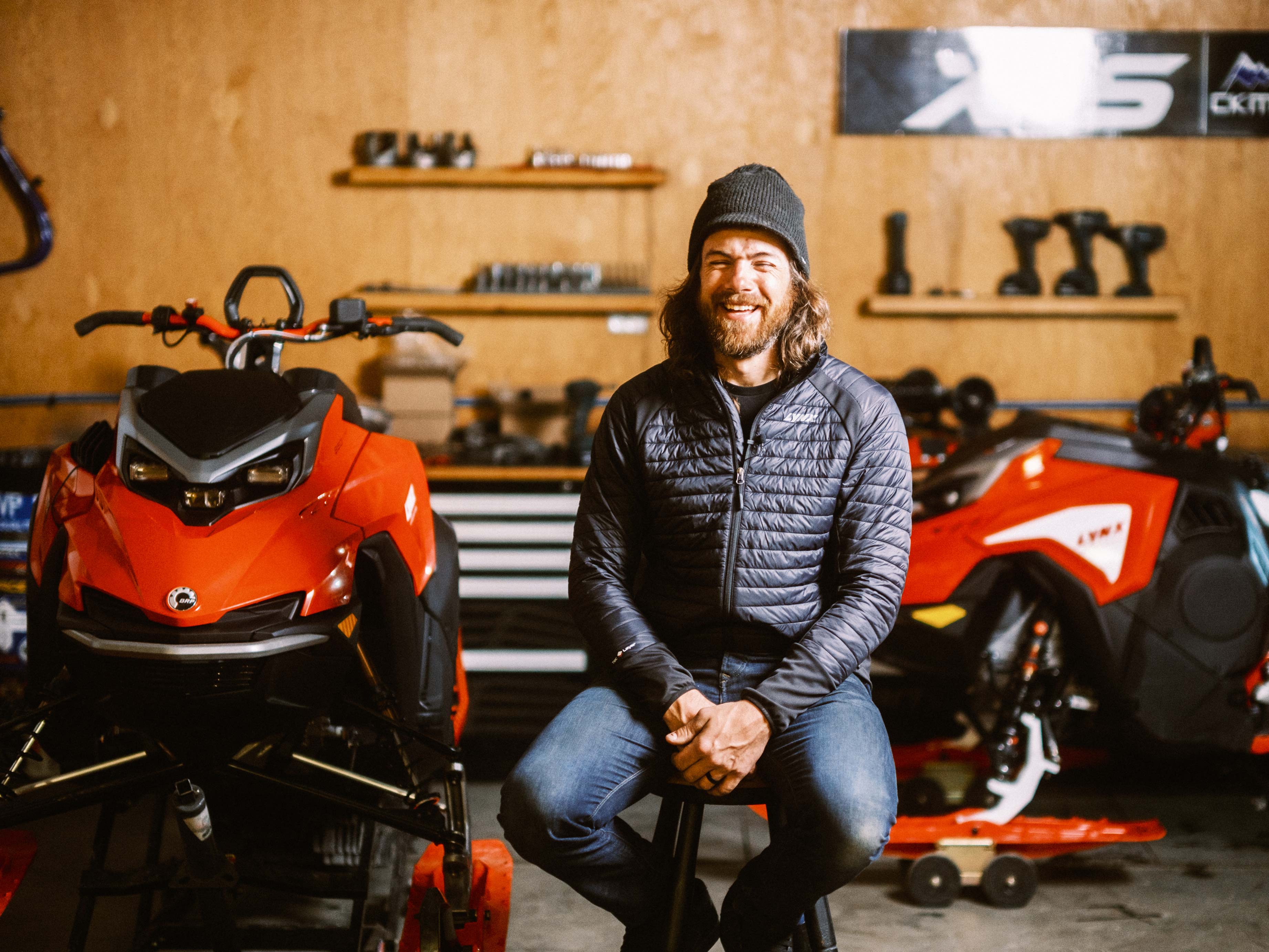 Jason Ribi sitting in front of Lynx sled in a garage