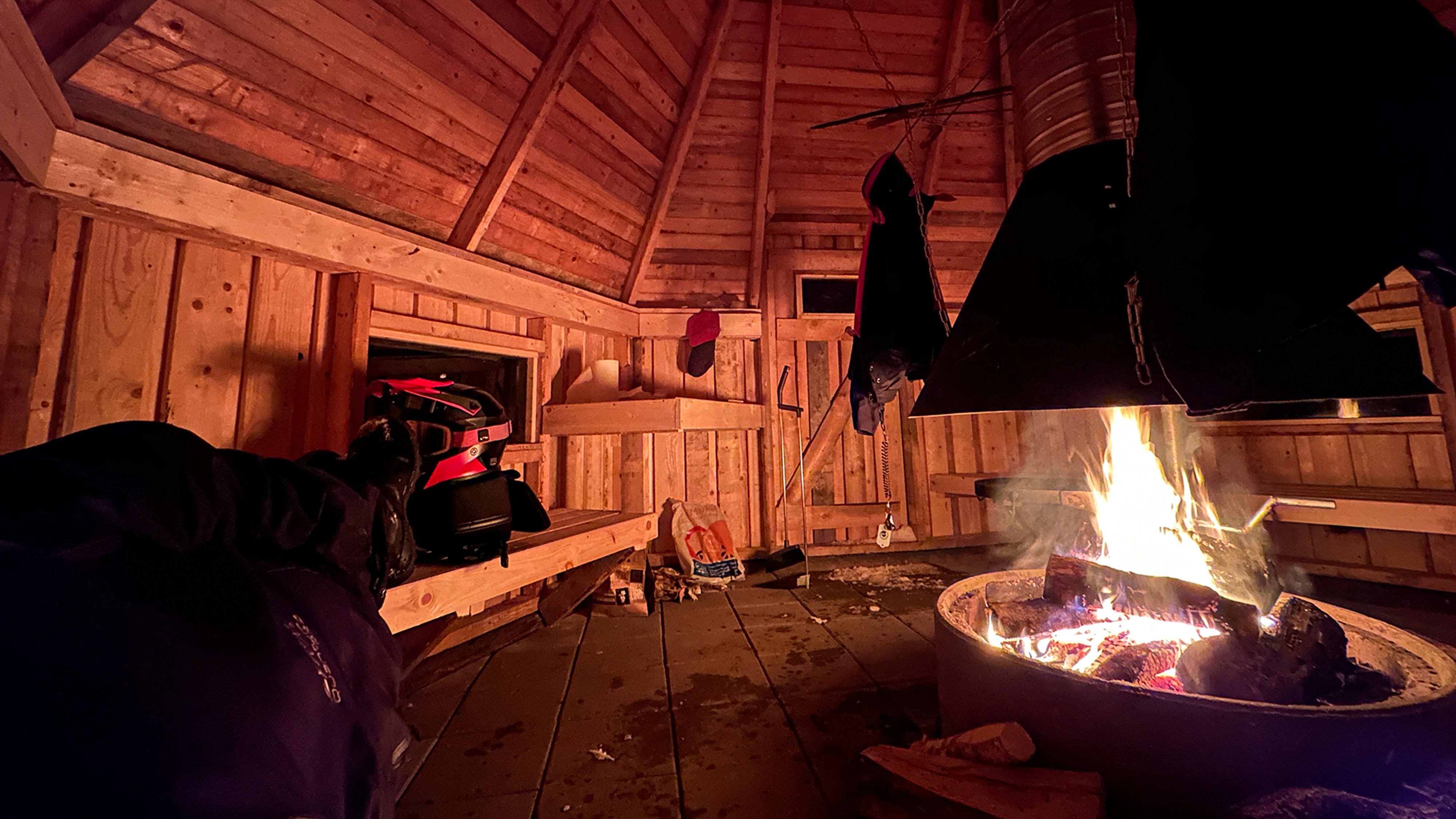 Joni Maununen laying next to a campfire in a shelter