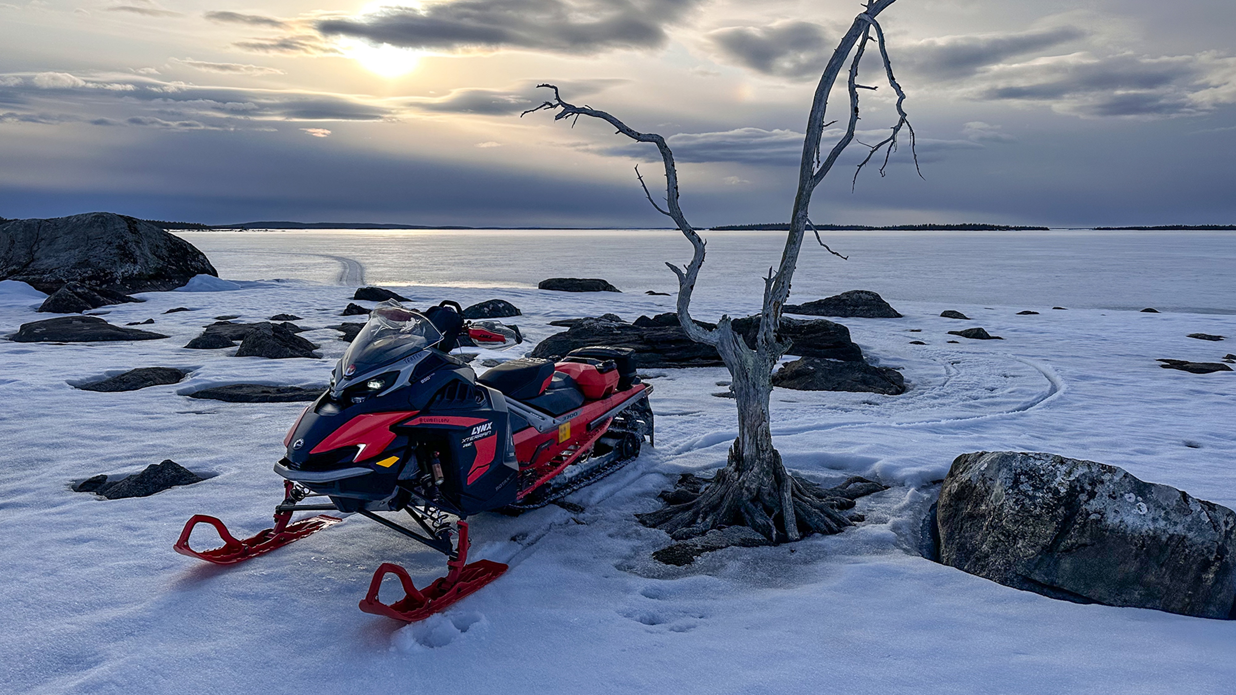 Lynx Xterrain RE 850 E-TEC crossover snöskoter parkerad på stranden av en isig sjö