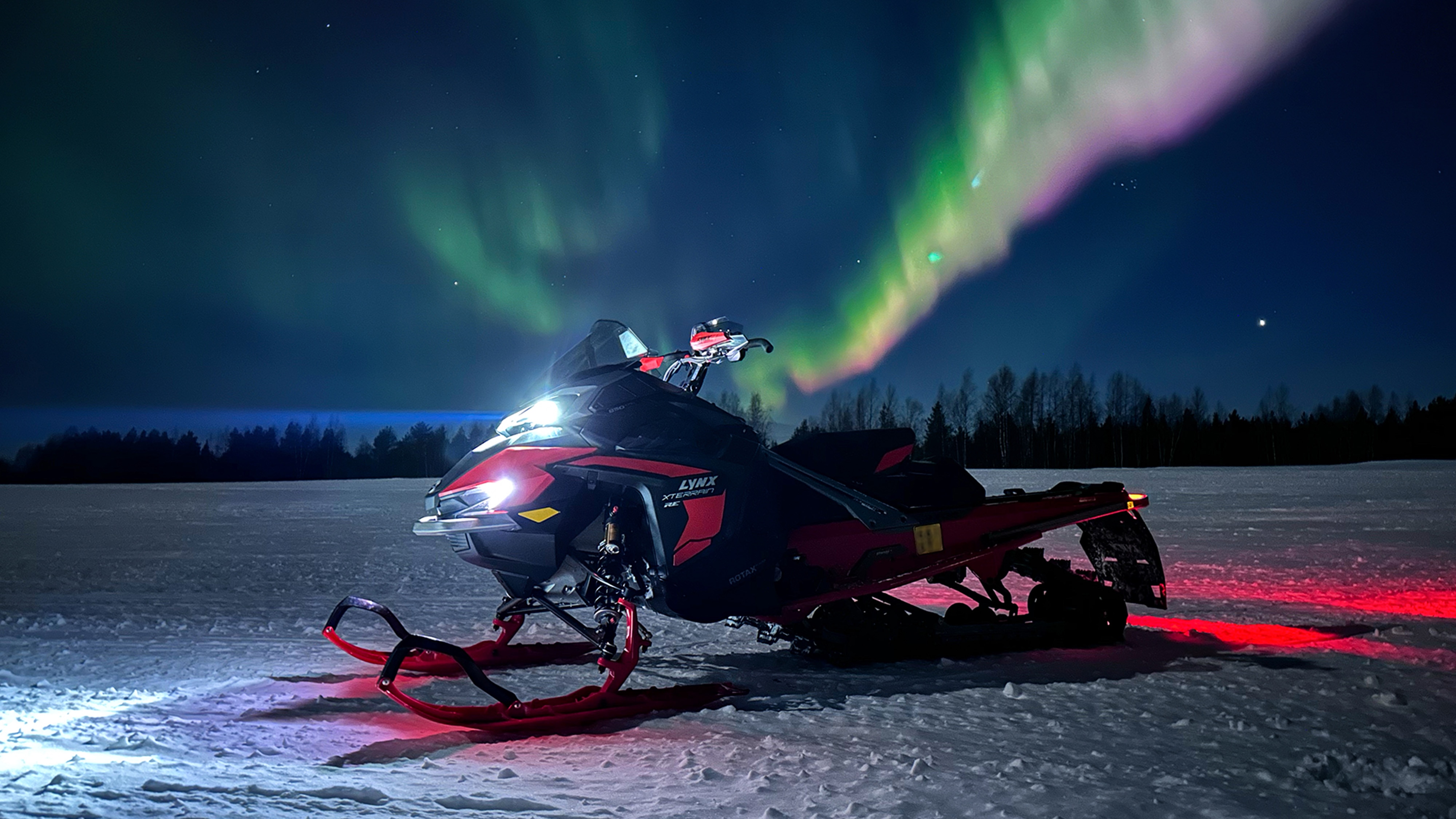 Lynx Xterrain RE 850 E-TEC crossover snowmobile parked under northern lights