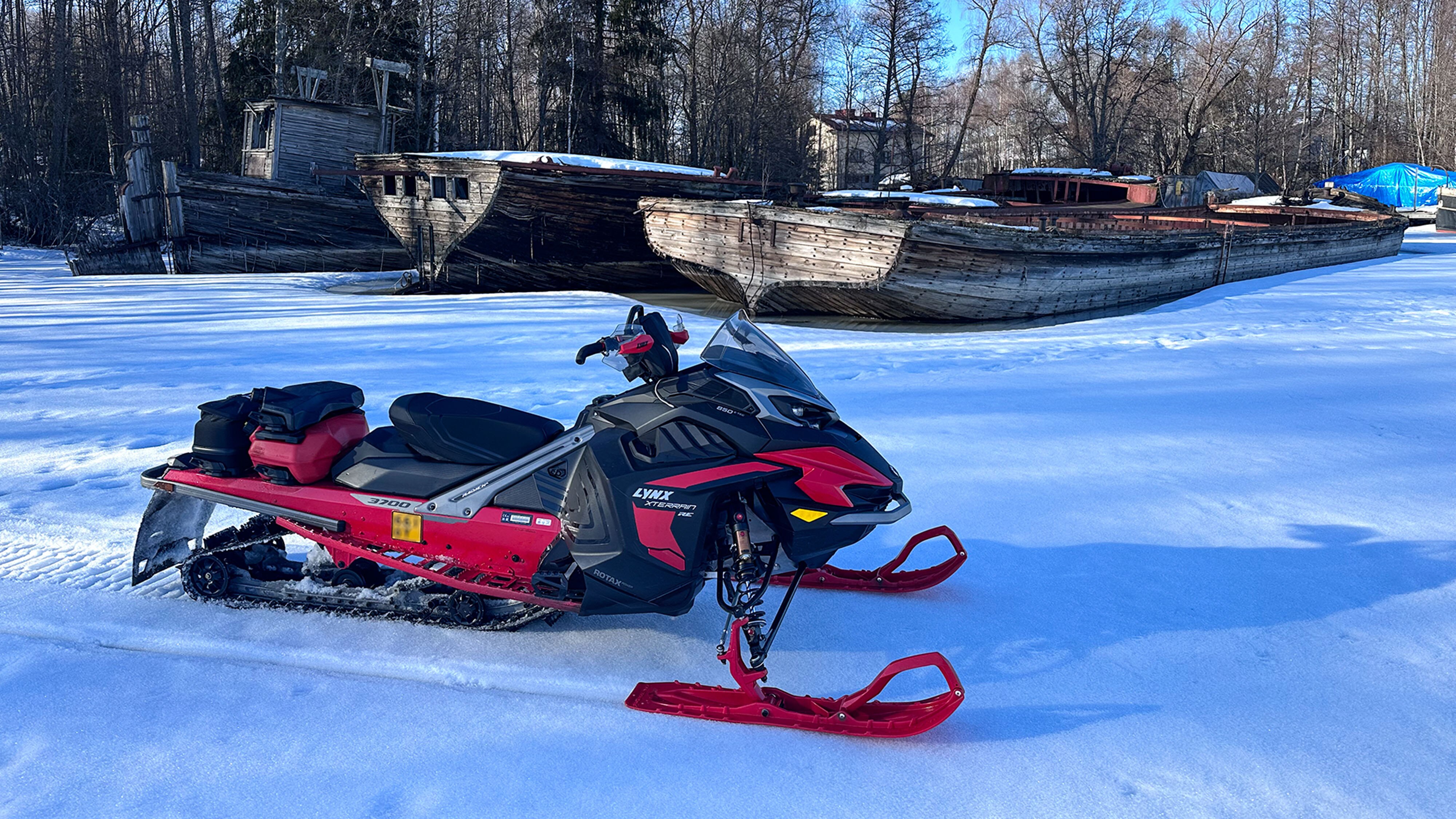 Lynx Xterrain RE 850 E-TEC crossover-snøscooter parkert ved siden av gamle innsjøbåter.