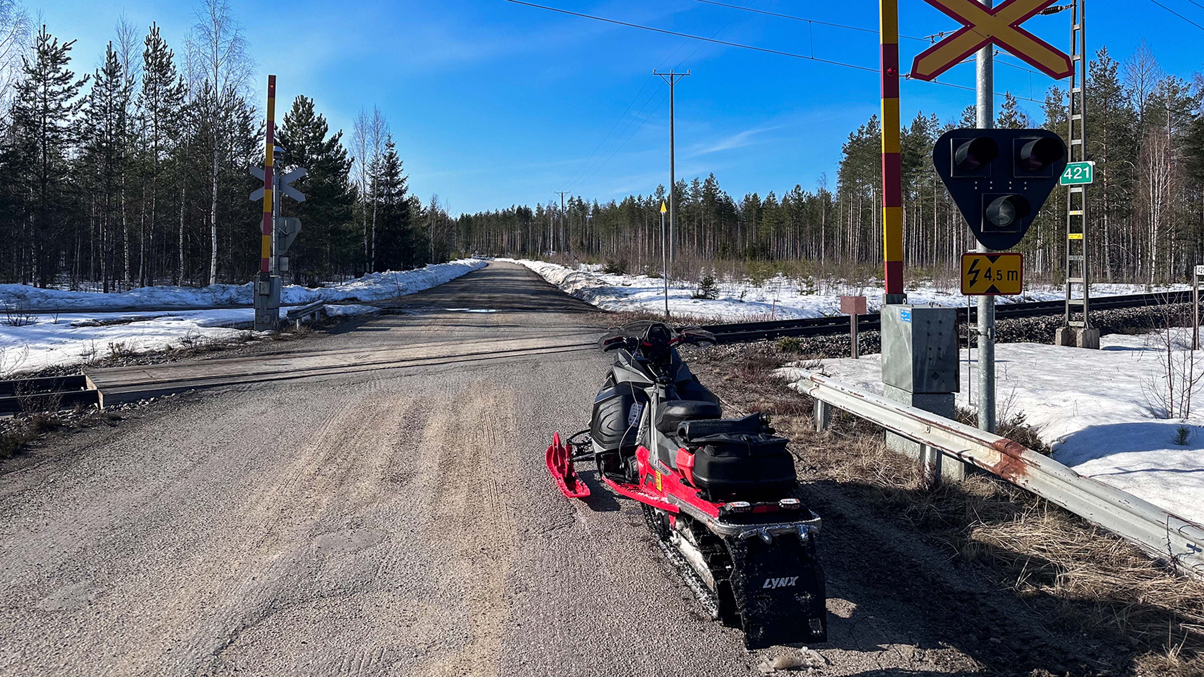 Lynx Xterrain RE 850 E-TEC -crossover-moottorikelkka ylittämässä rautatietä soratietä pitkin